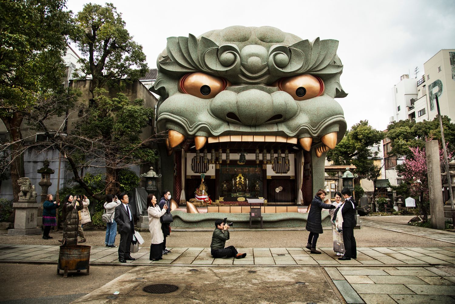 Traditional Japanese temple entrance with large sculptural lanterns and visitors exploring the grounds.
