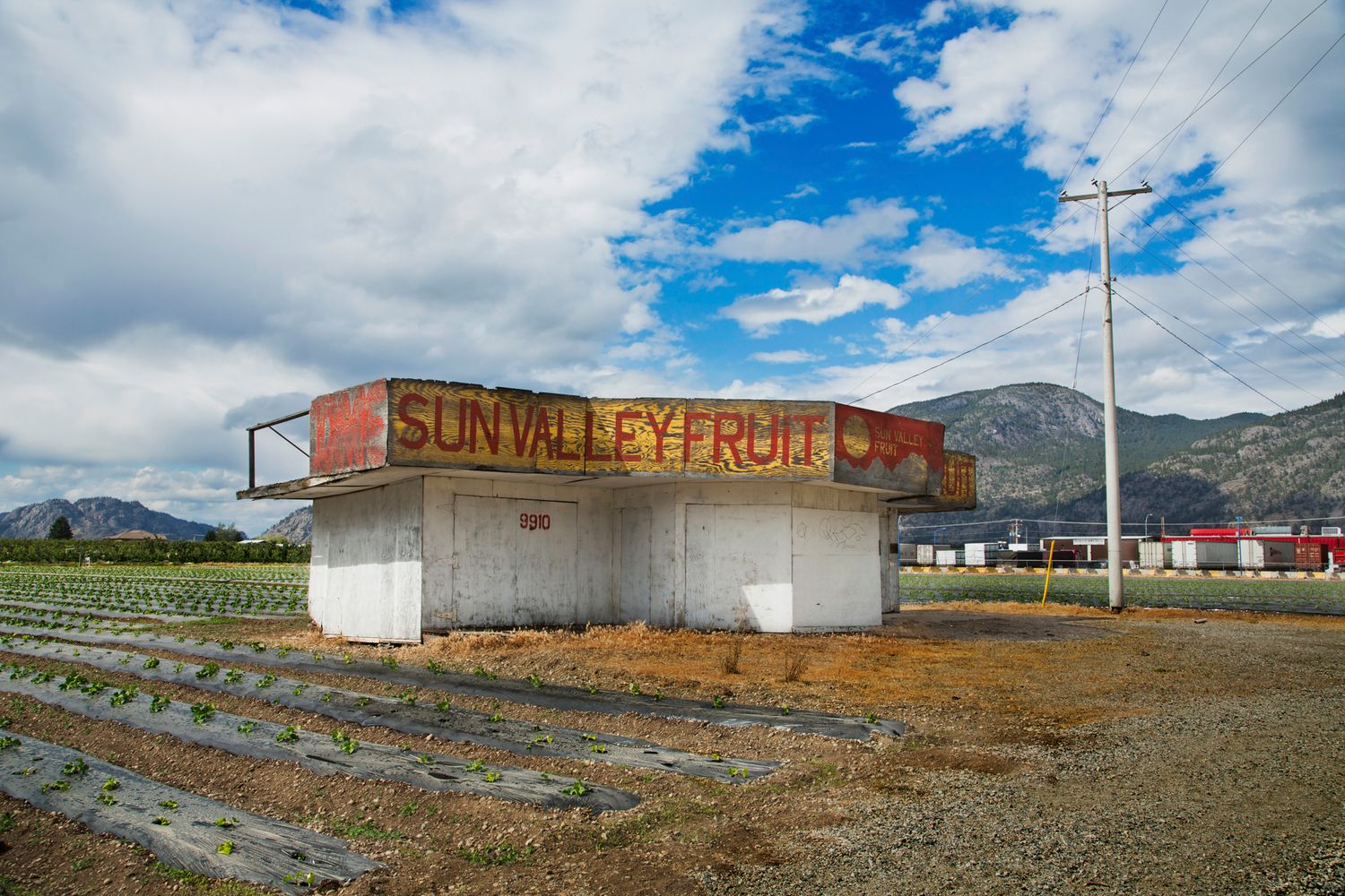 Abandoned Sunnyside Fruit roadside stand with mountains in background under blue skies.