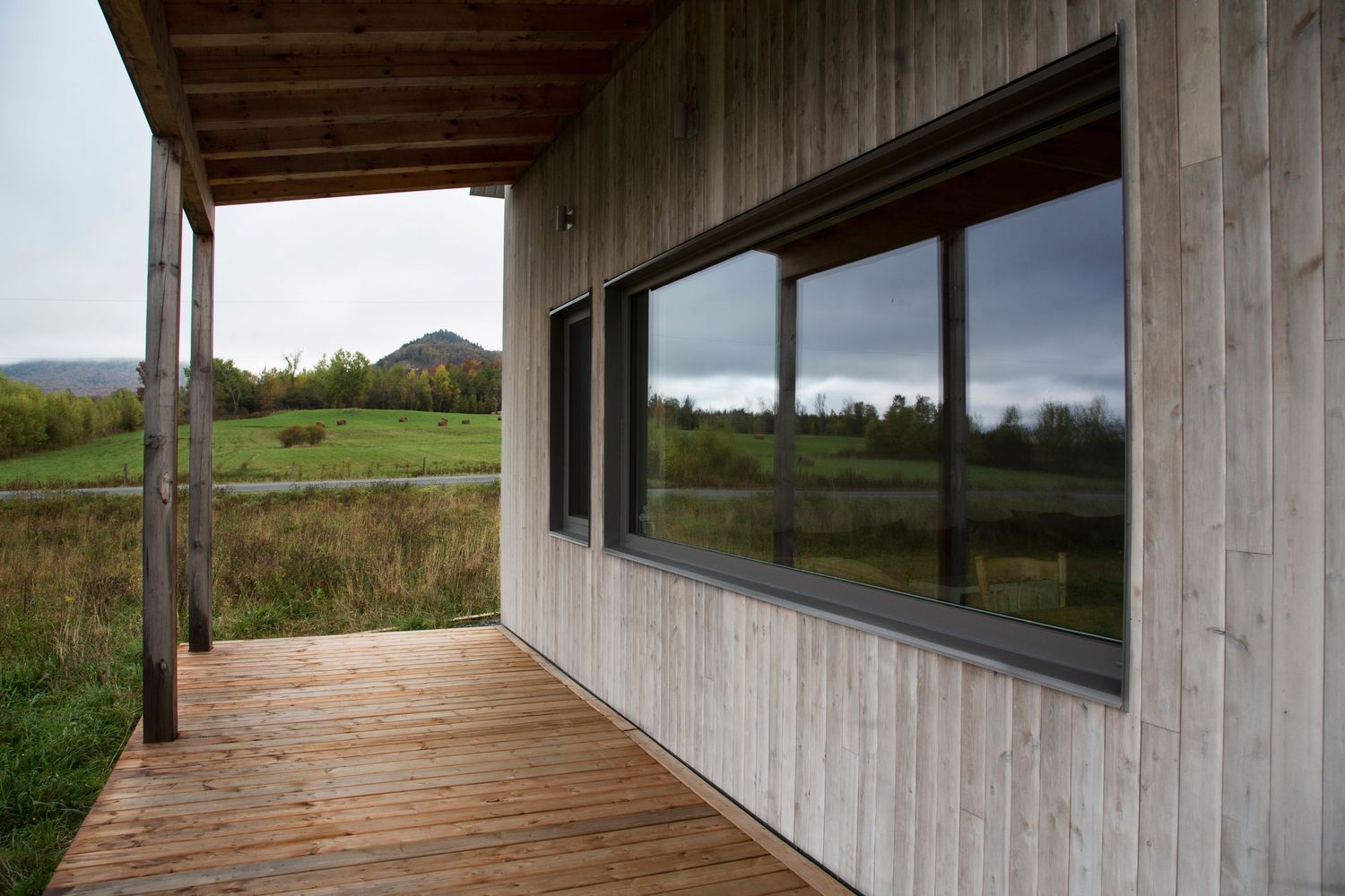 Wooden deck and porch detail of modern house with panoramic countryside views.