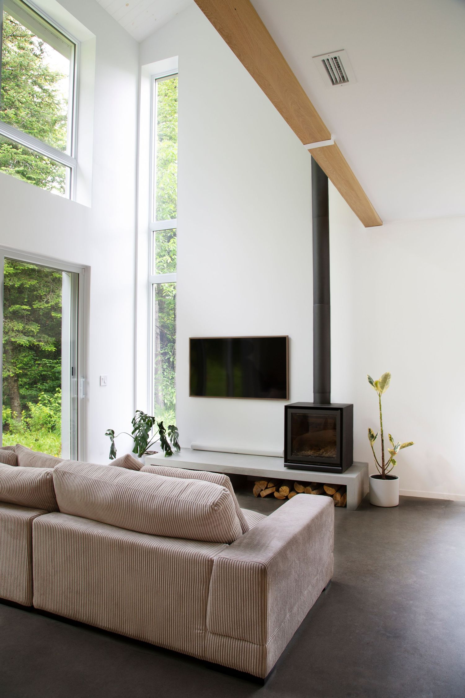 Modern living room with high ceilings, large windows, and a gray sectional sofa facing a sleek fireplace.