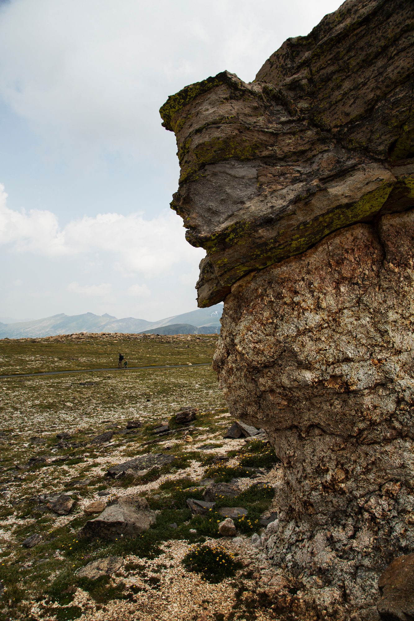 Rugged rocky outcrops and cliffs overlook a barren desert landscape with distant mountains on the horizon.
