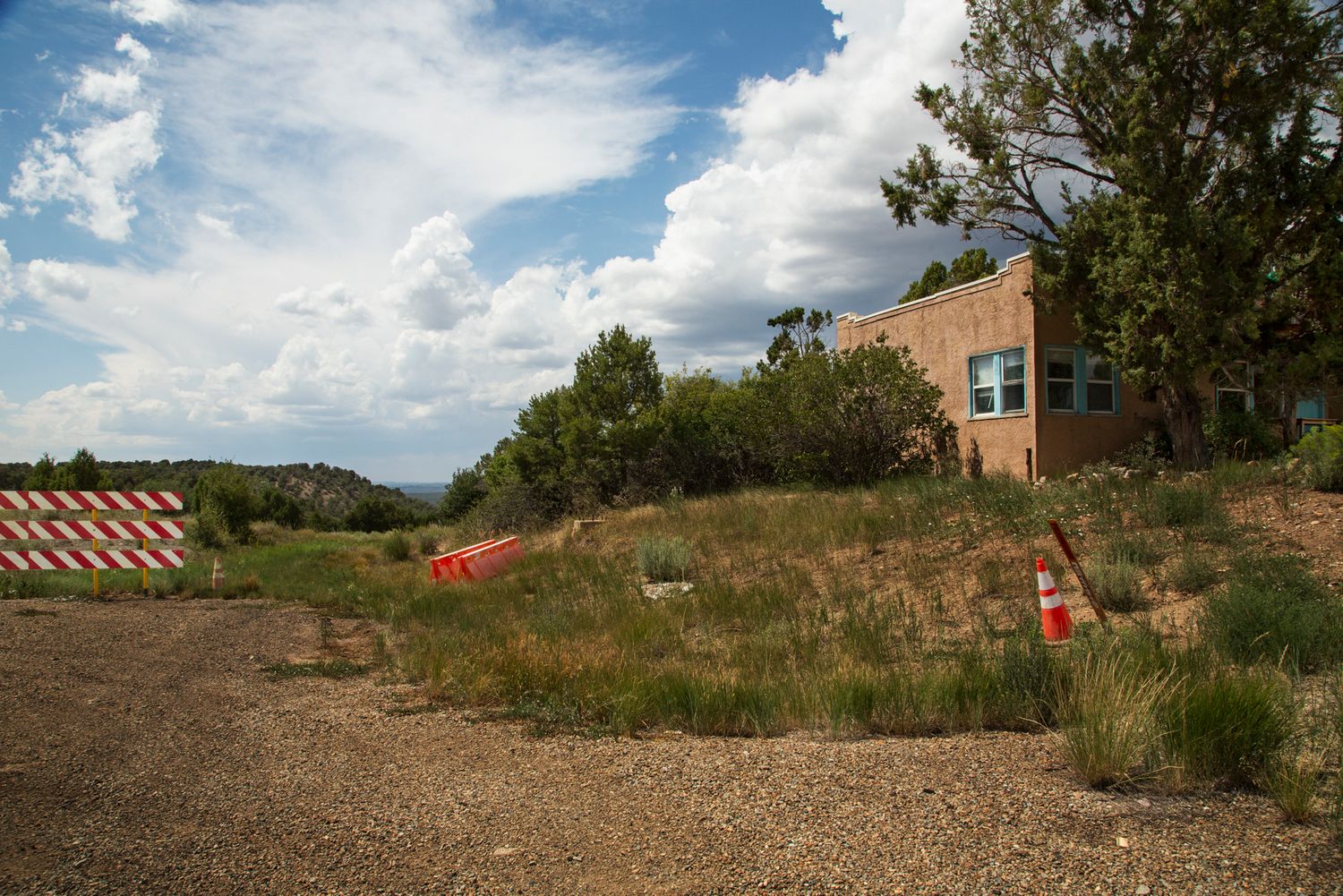 A panoramic view of a construction site with orange safety barriers and a building in the background under blue skies.