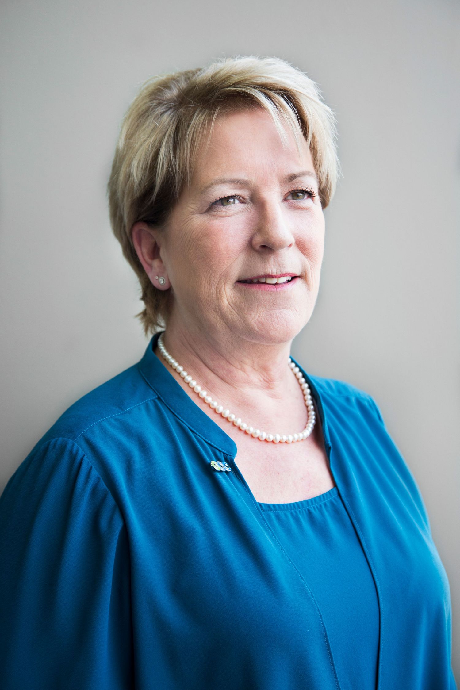 Portrait series showing different angles and expressions while wearing a blue top and pearl necklace.