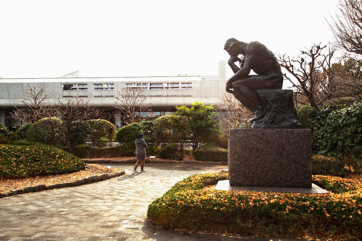 Bronze sculpture in a manicured garden setting with winter trees.