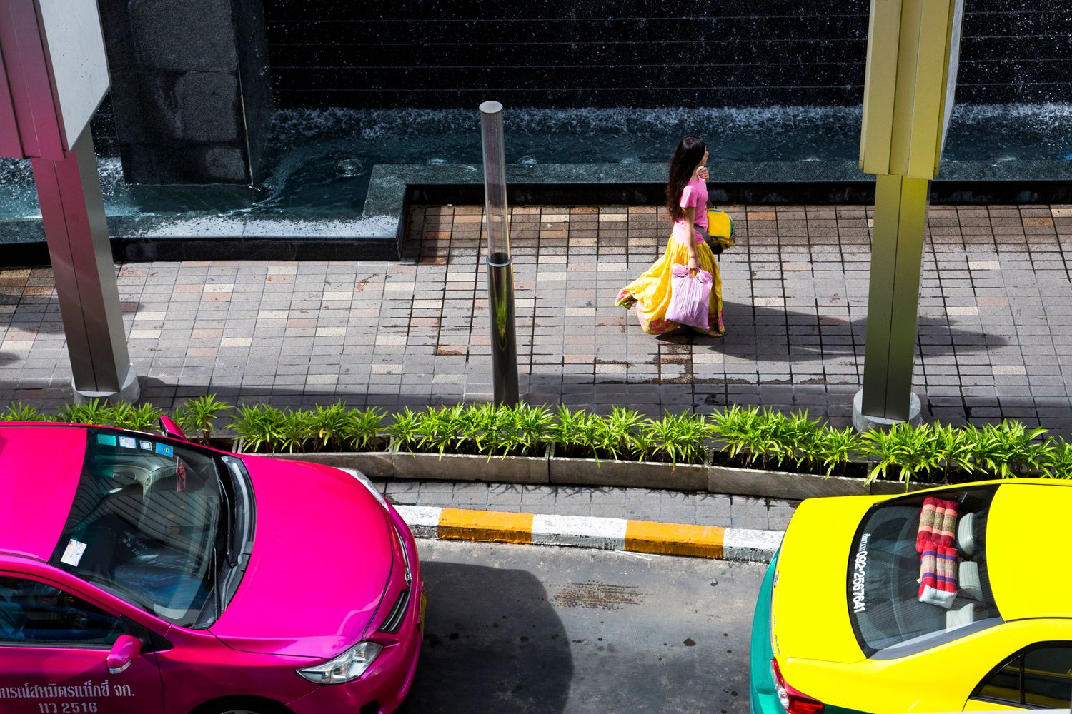 Colorful taxis and urban street scene viewed from above with vibrant pink and yellow vehicles.