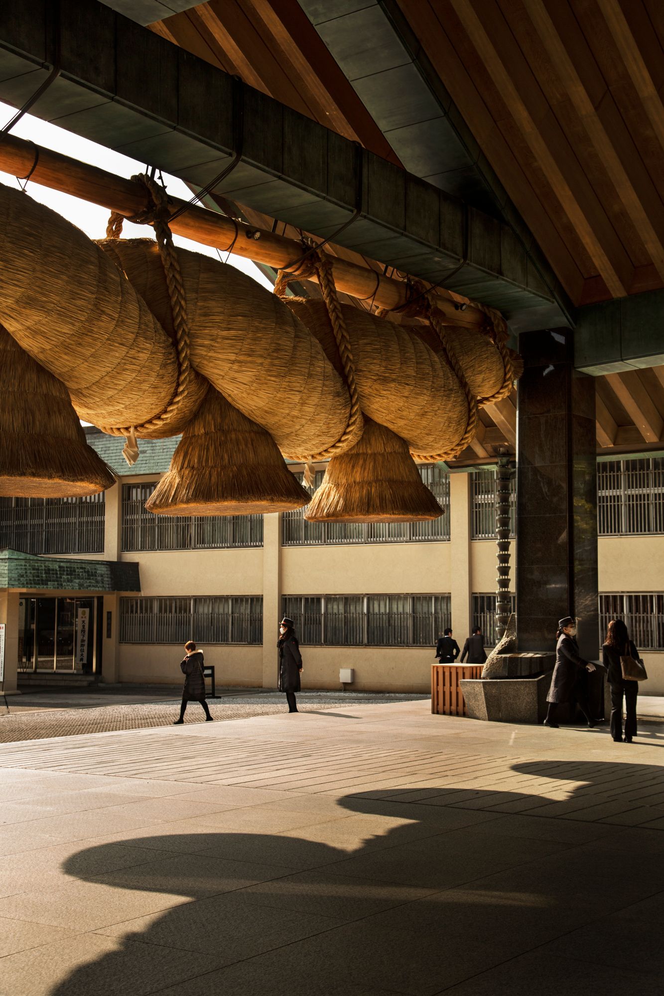 Large woven straw objects hang from wooden beams in spacious indoor venue.