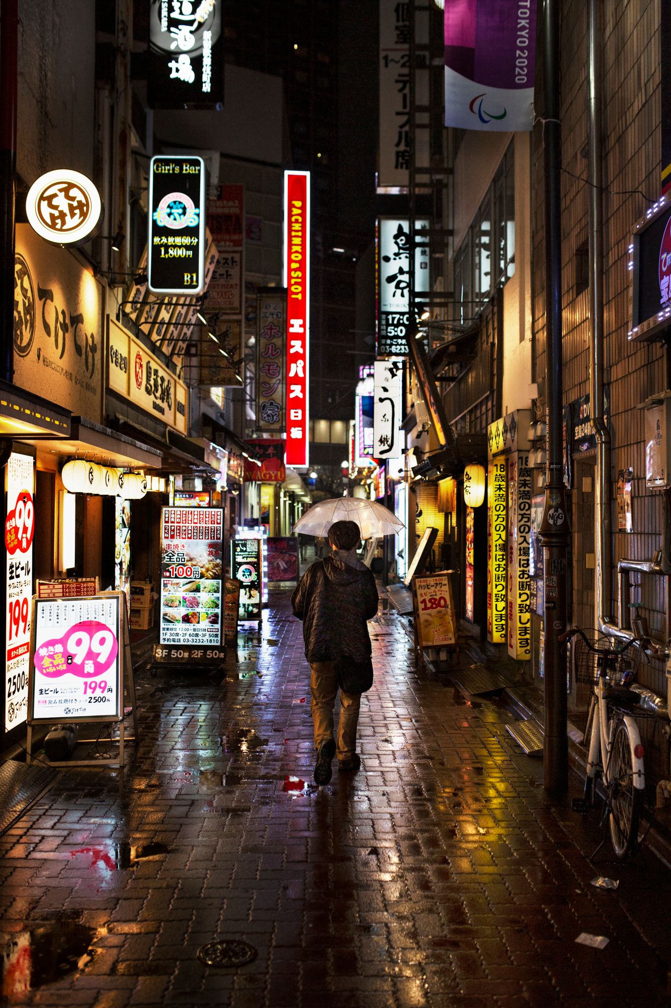 Rain-slicked street at night with glowing shop signs and neon lights in Japan.