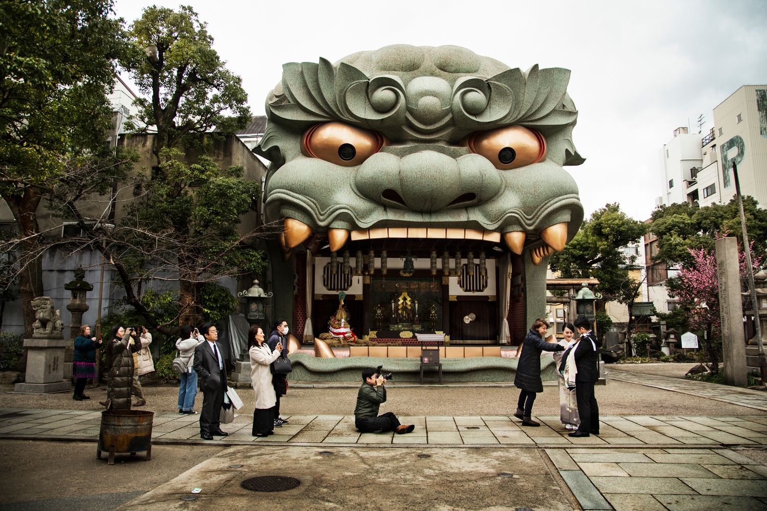Dramatic demon face entrance gate at a Japanese temple with visitors in the foreground.