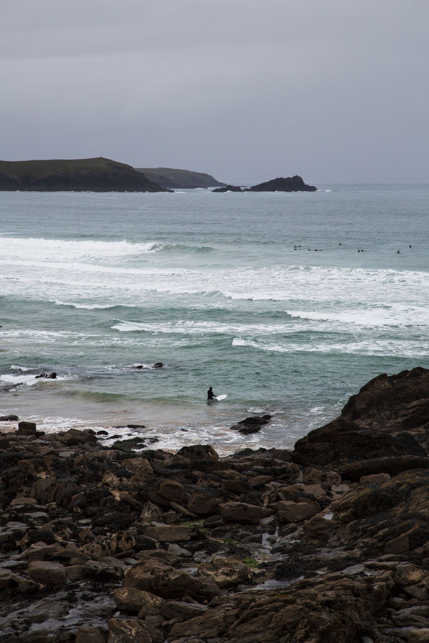 Rocky coastline with crashing waves and distant cliffs along a moody seashore.