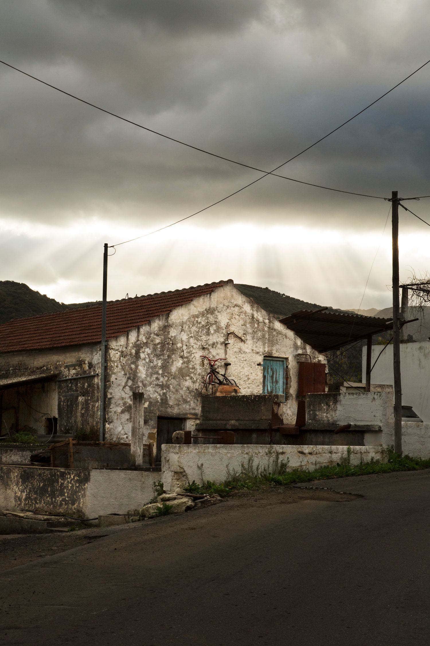 Row of weathered white buildings under stormy skies on a desolate street.