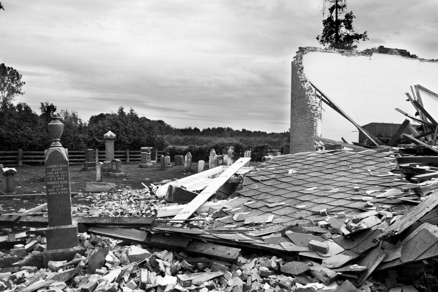 A series of black and white photographs showing severe tornado damage to buildings and structures in a rural area.