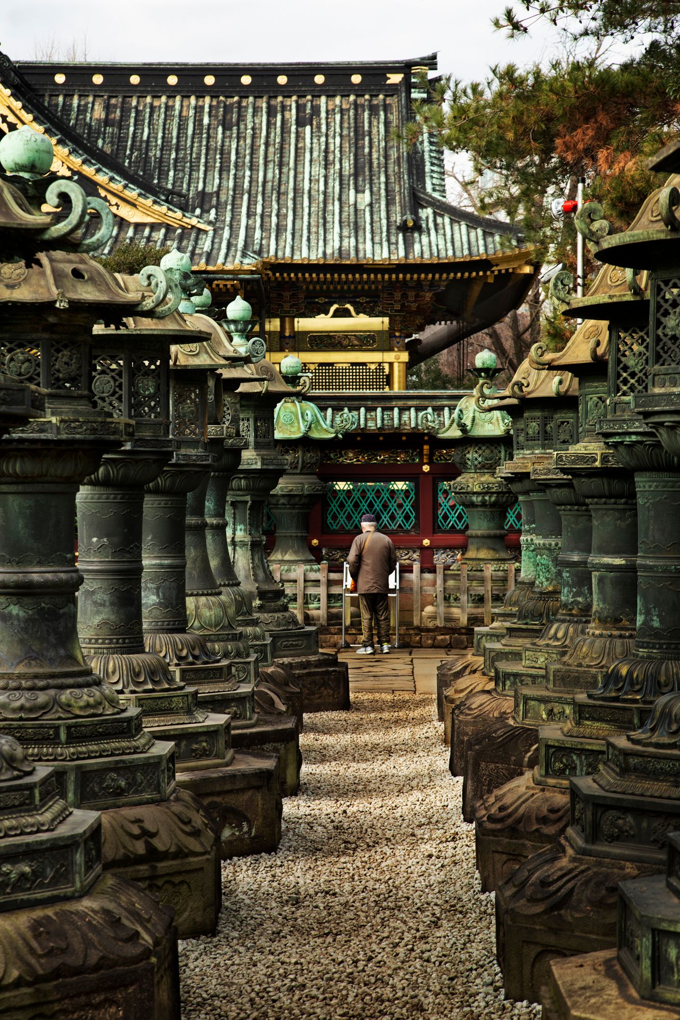 Ancient stone lanterns line a gravel path at a traditional Japanese temple.