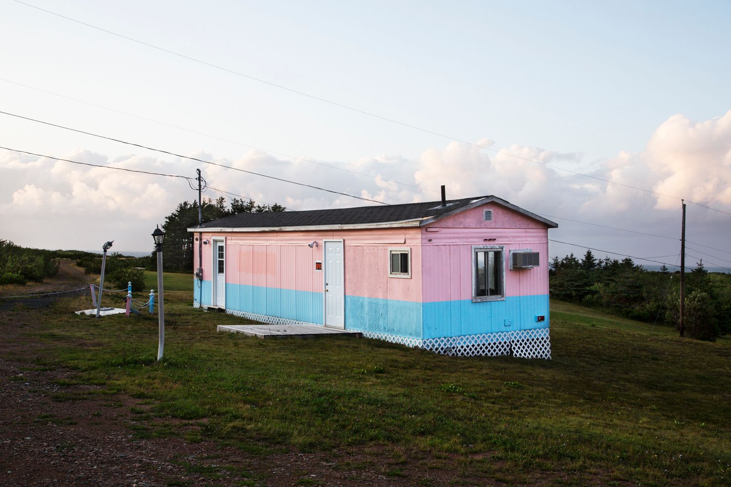 Pink houses dot a rugged coastal landscape under cloudy skies along the shoreline.