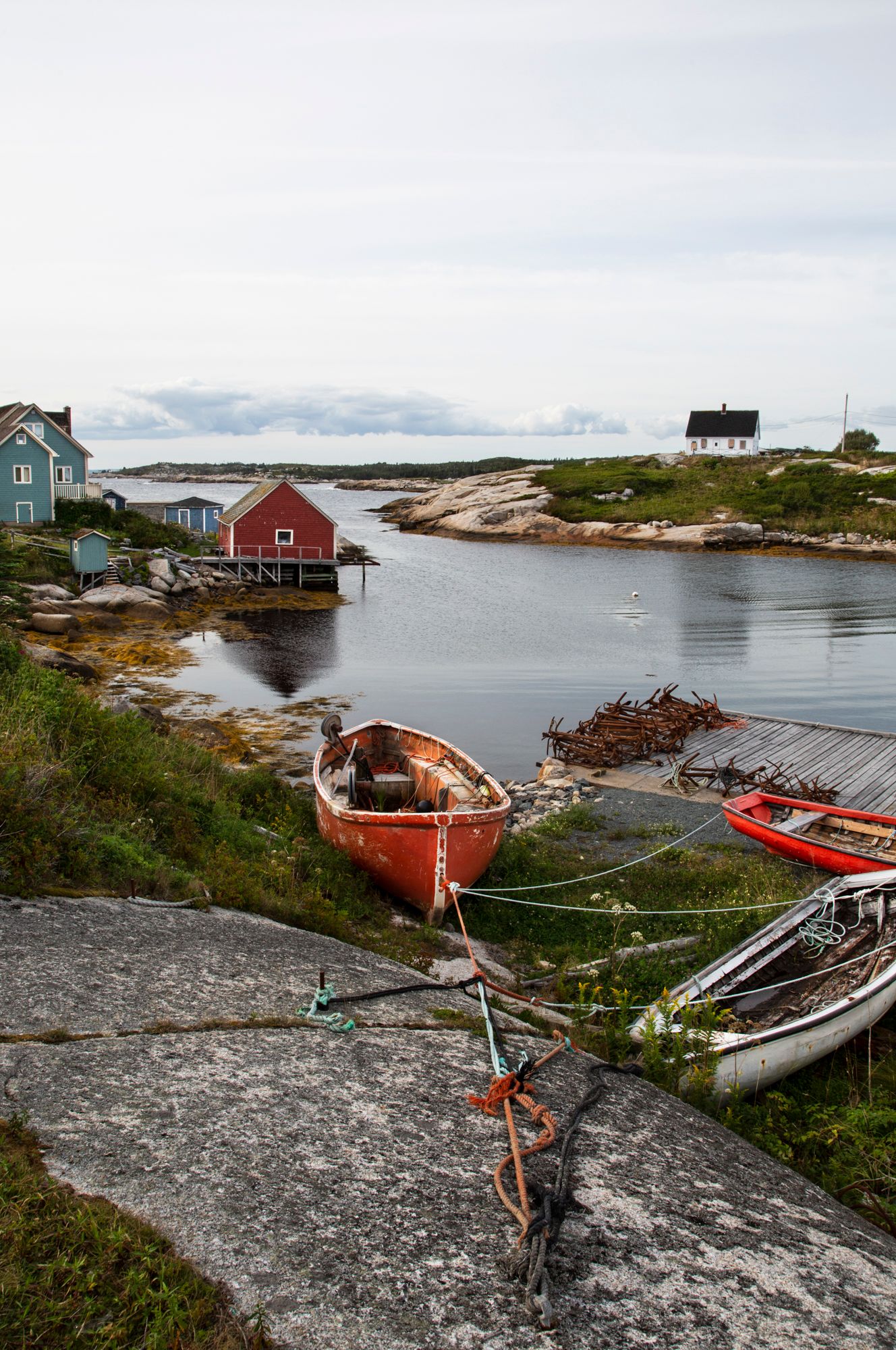 Colorful fishing village with wooden houses and boats along a rocky Nova Scotia coastline.