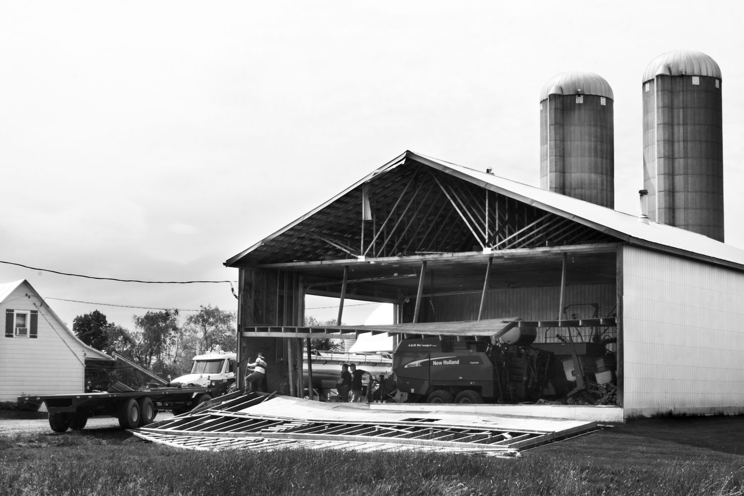 A series of black and white photographs showing farm buildings, silos, and barns in a rural agricultural setting.