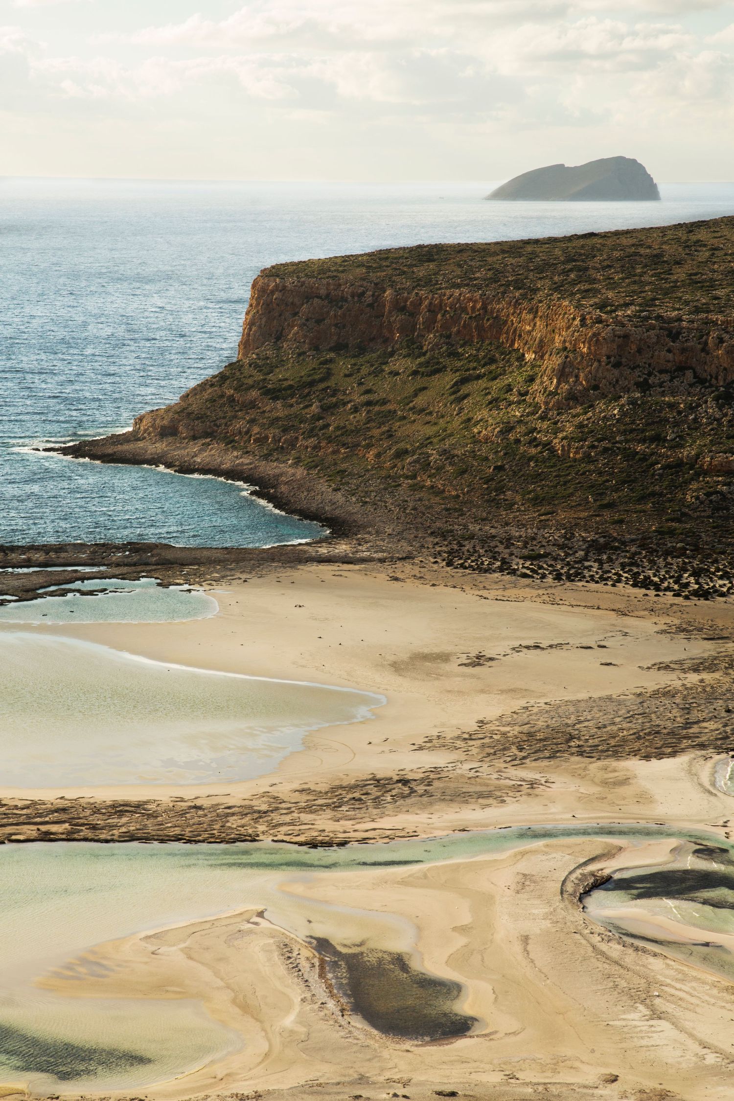 Aerial view of a secluded beach cove with turquoise waters surrounded by rocky cliffs.