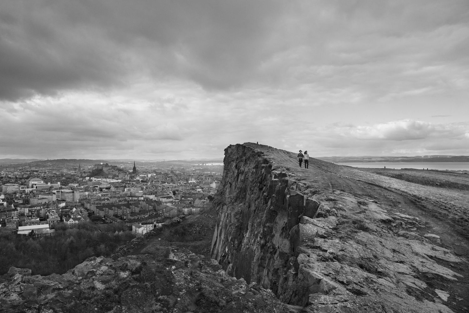 Panoramic view of a rugged Scottish highland landscape with dramatic cloudy skies and rocky cliffs.
