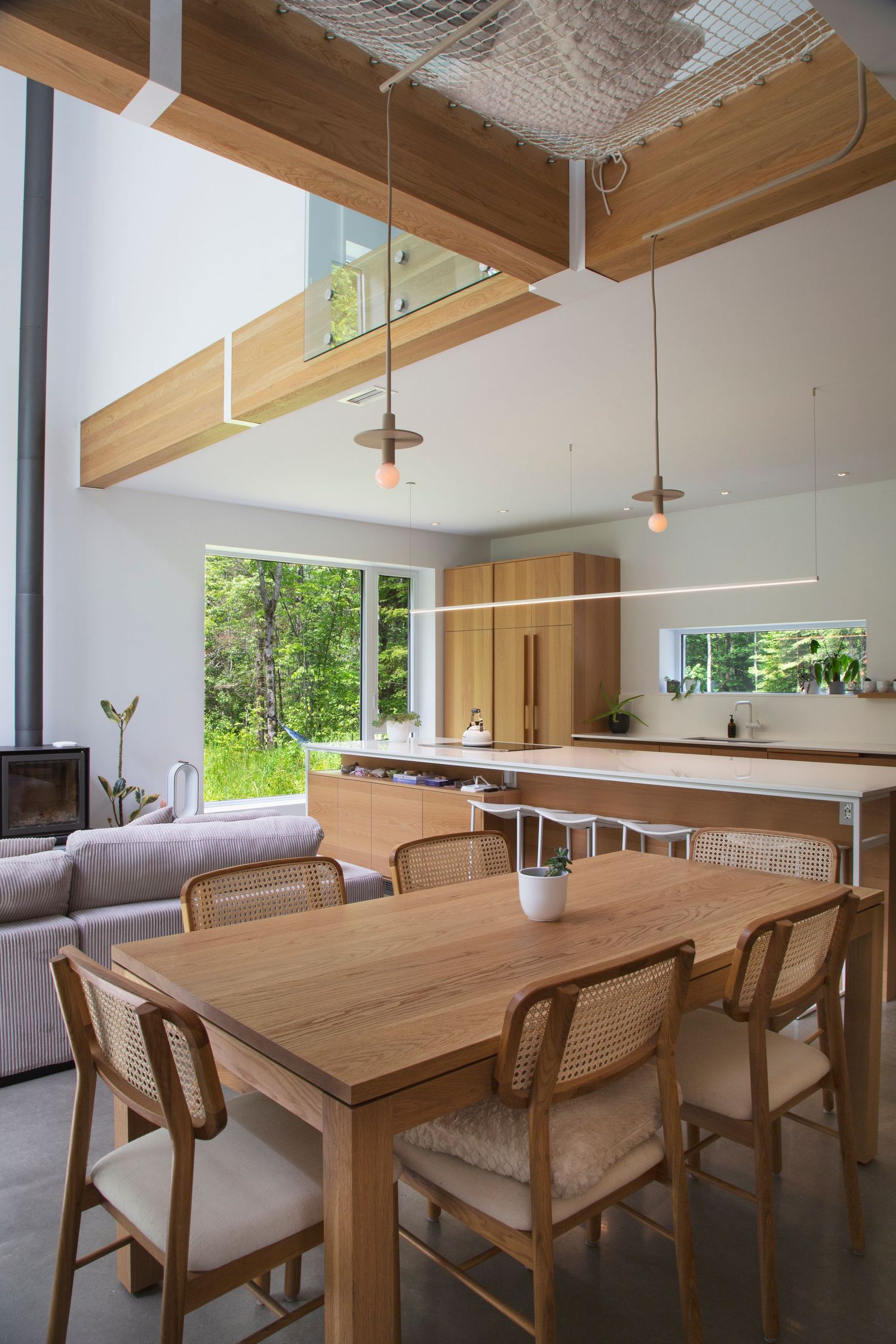 Modern dining room featuring wooden tables, cane chairs, and natural light from large windows.