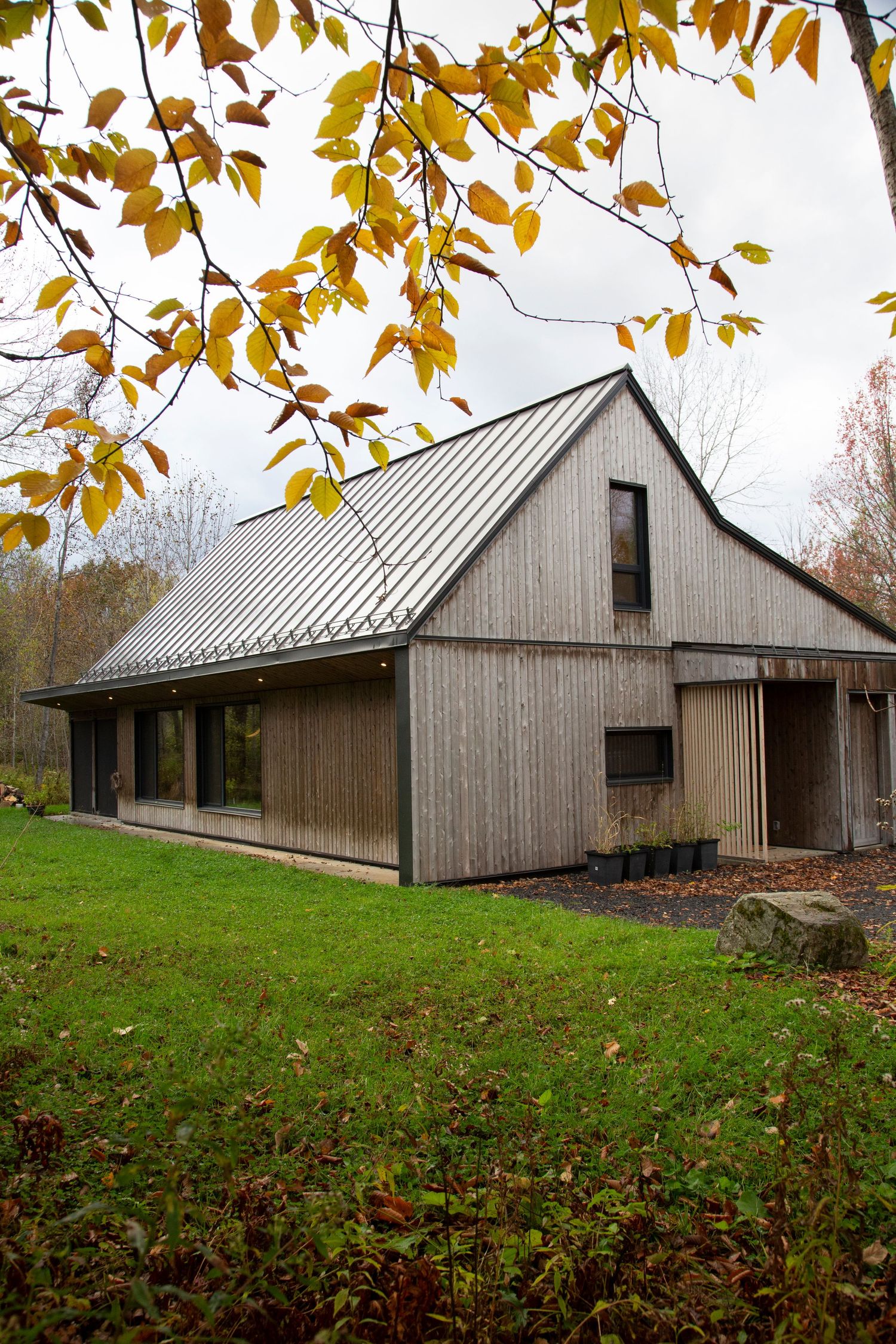 Rustic wood-sided building with metal roof surrounded by fall foliage.