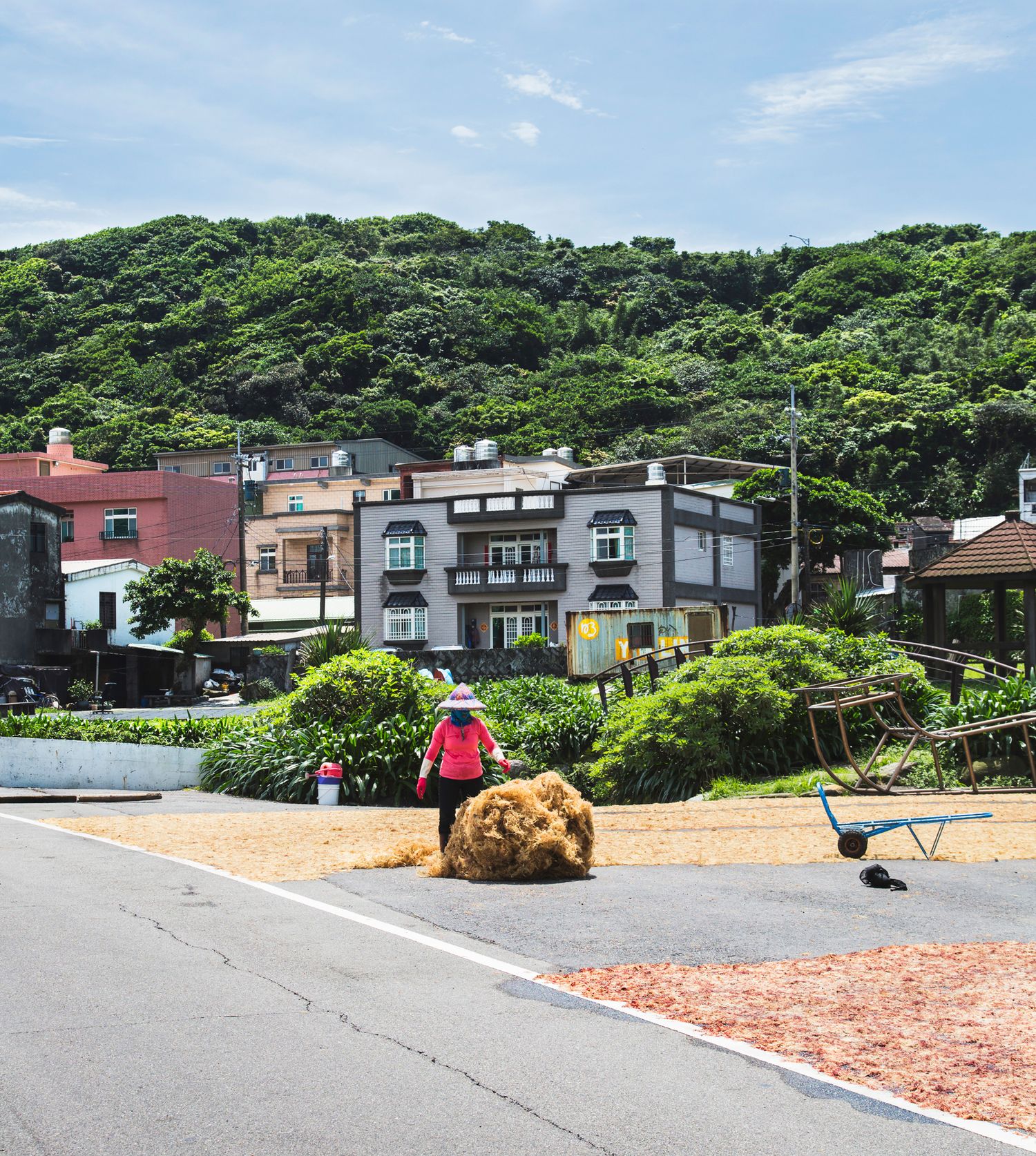 Residential street in Japanese town with houses nestled against lush green hillside.