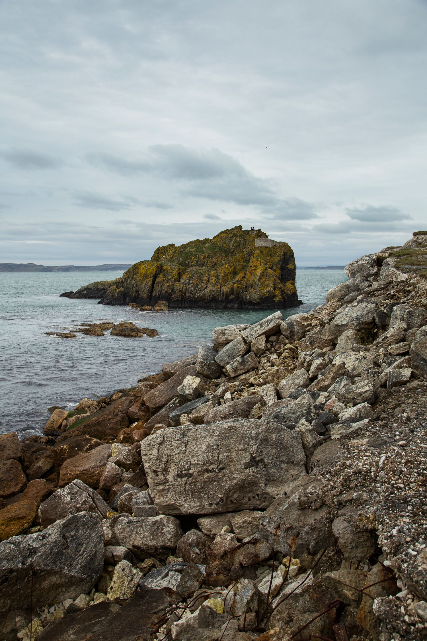 Rugged rocky shoreline with scattered boulders and waves crashing against coastal outcrops.