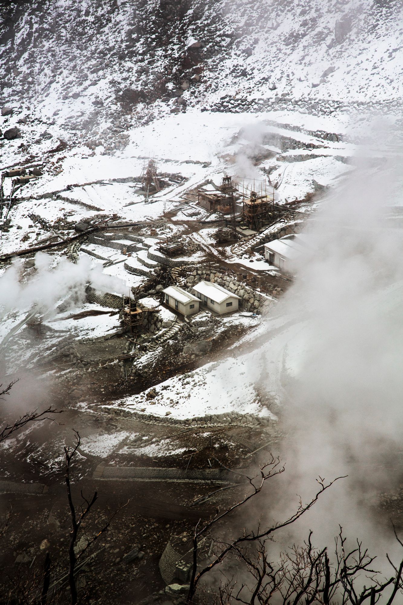 Aerial view of a snow-covered mountain village with buildings and infrastructure nestled in the terrain.