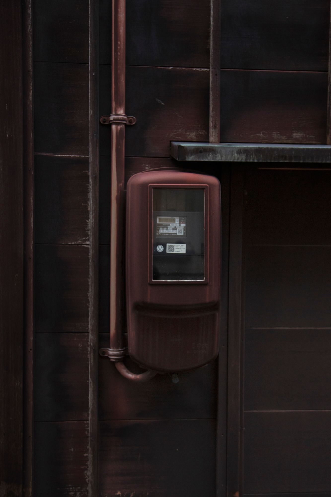 Dark wooden wall with electrical meters and utility boxes mounted on the surface.