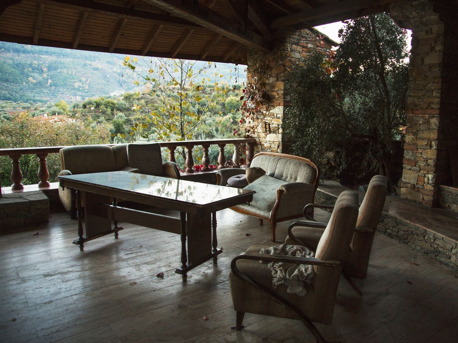 Stone veranda with outdoor seating overlooking a scenic mountain landscape.