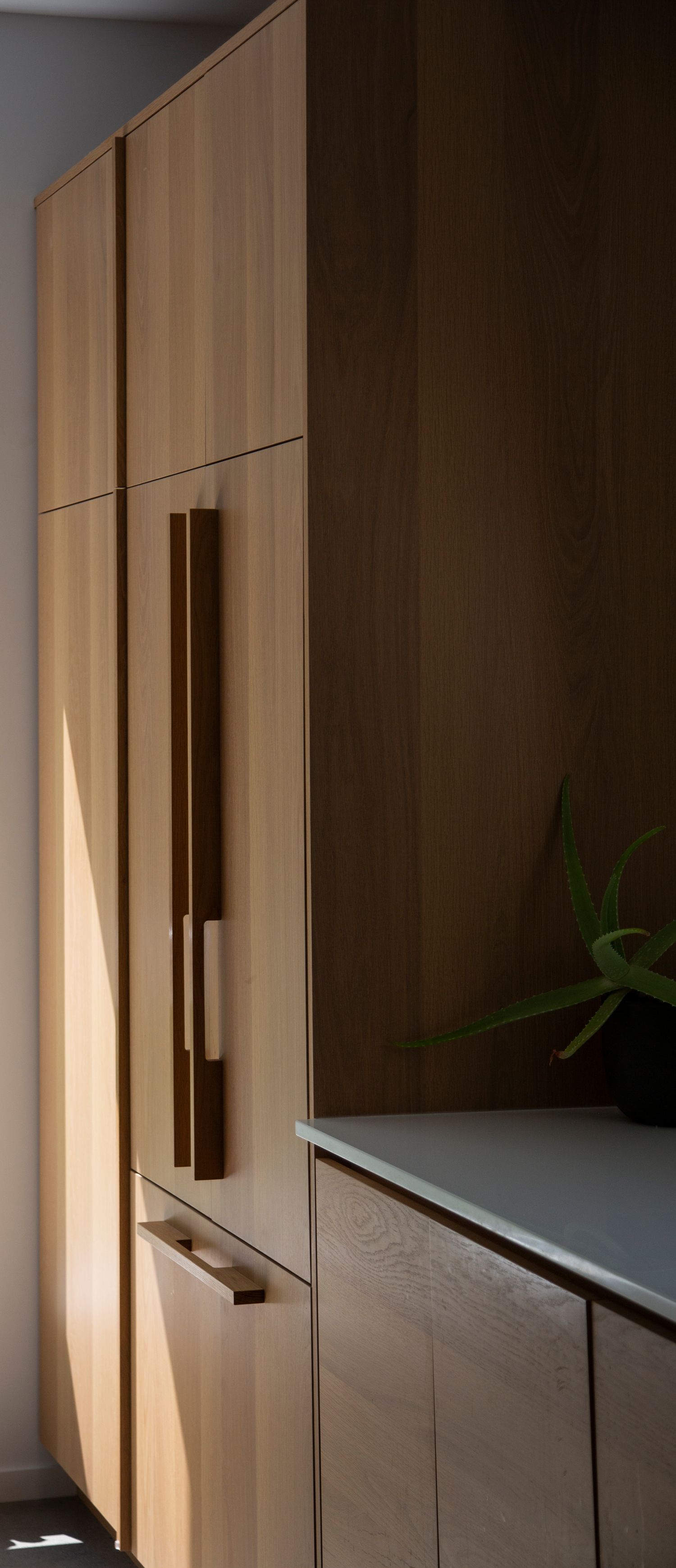Modern built-in wooden cabinets with sleek vertical handles create clean lines in a minimalist interior.