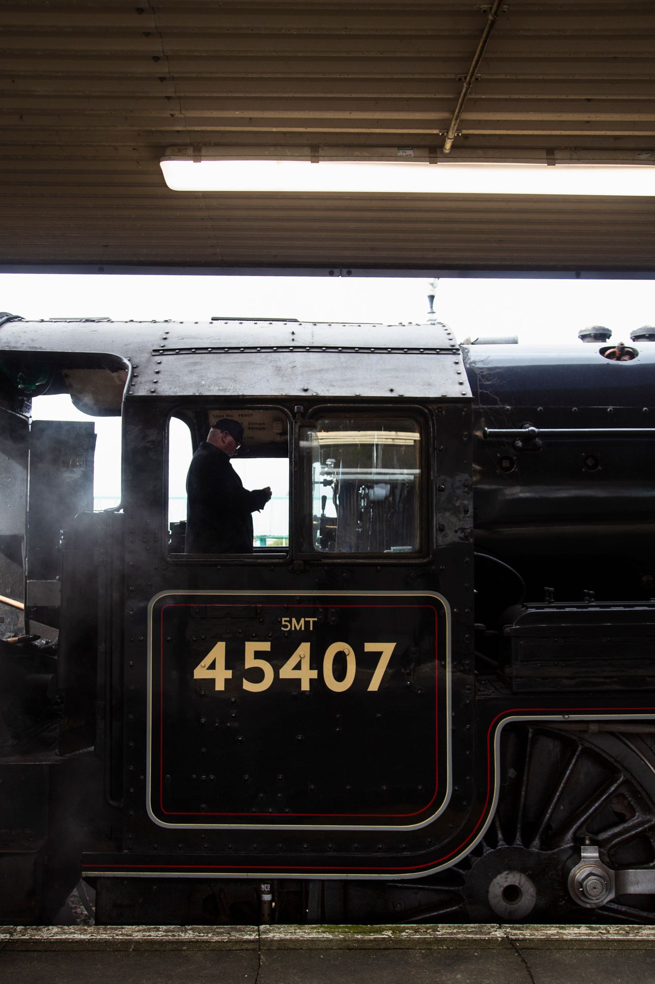 Close-up view of black steam locomotive number 45407 with gold lettering against dark background.