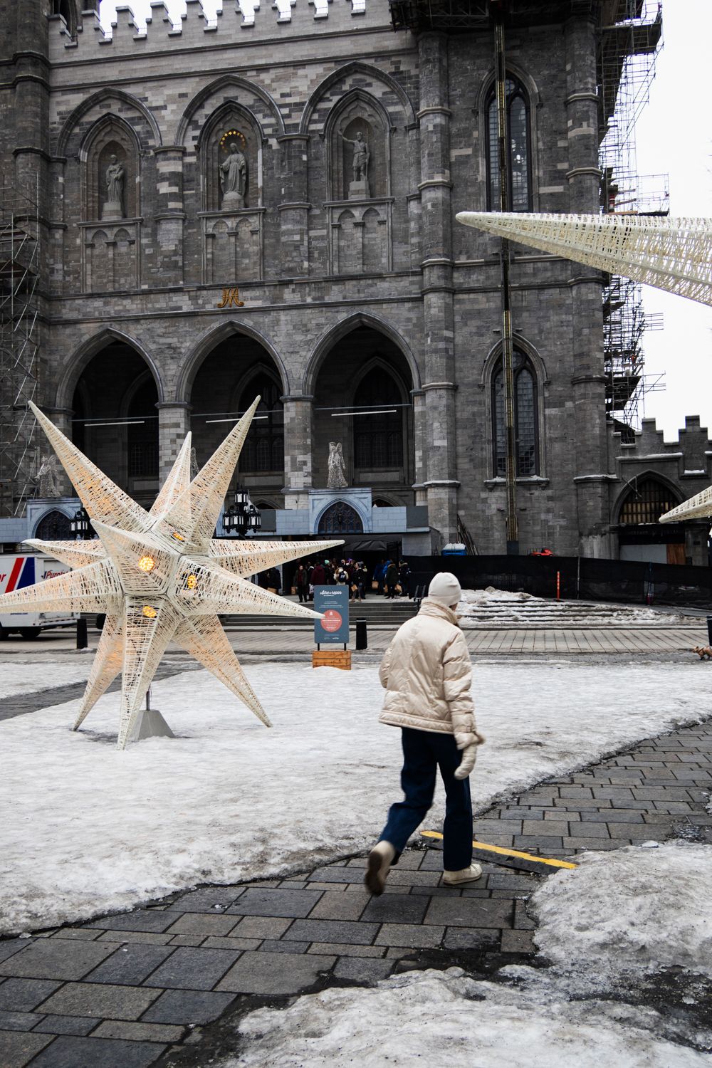 Large illuminated star decorations in front of a gothic stone church during winter.