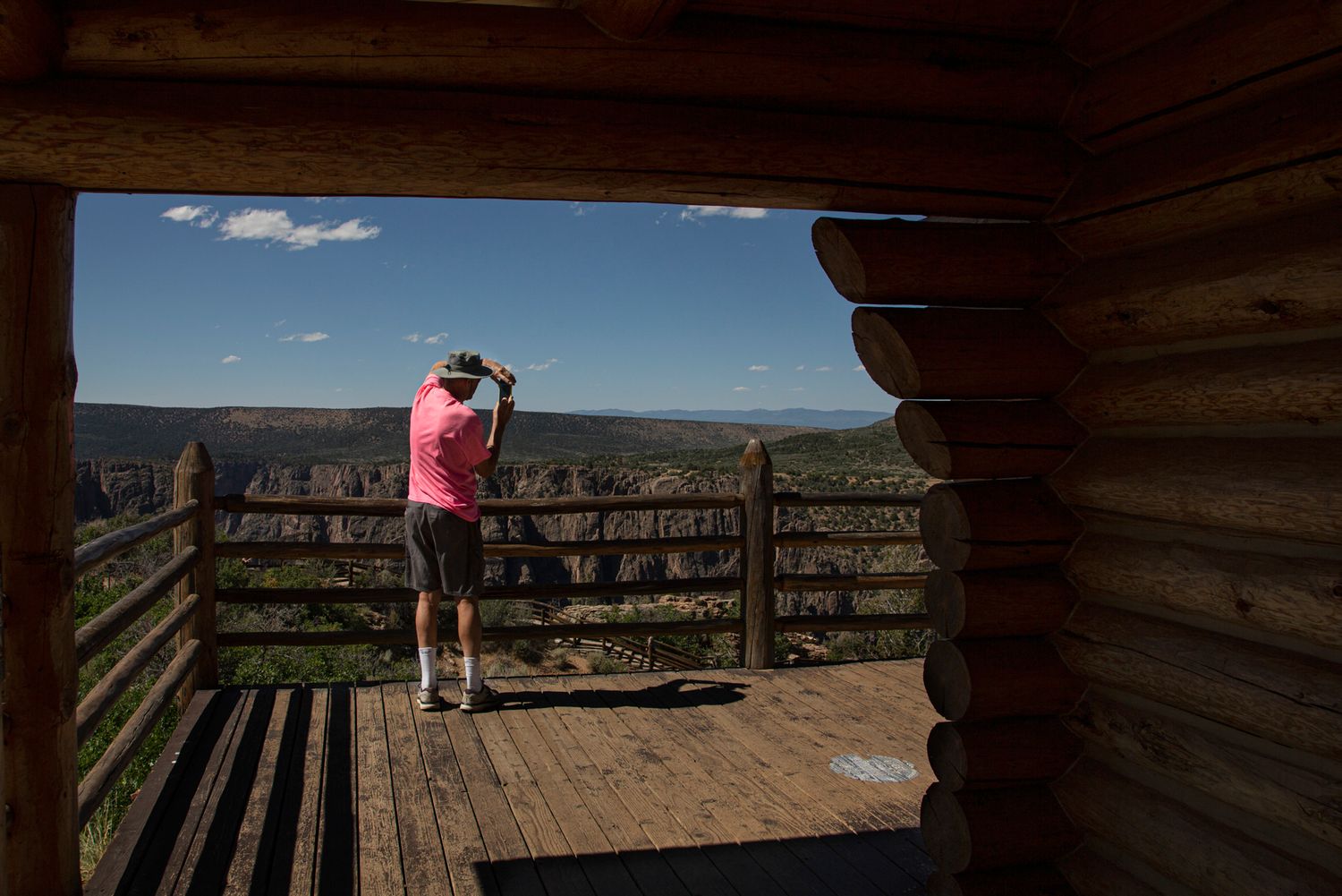 Person enjoying scenic mountain views from a wooden observation deck overlooking vast desert landscape.
