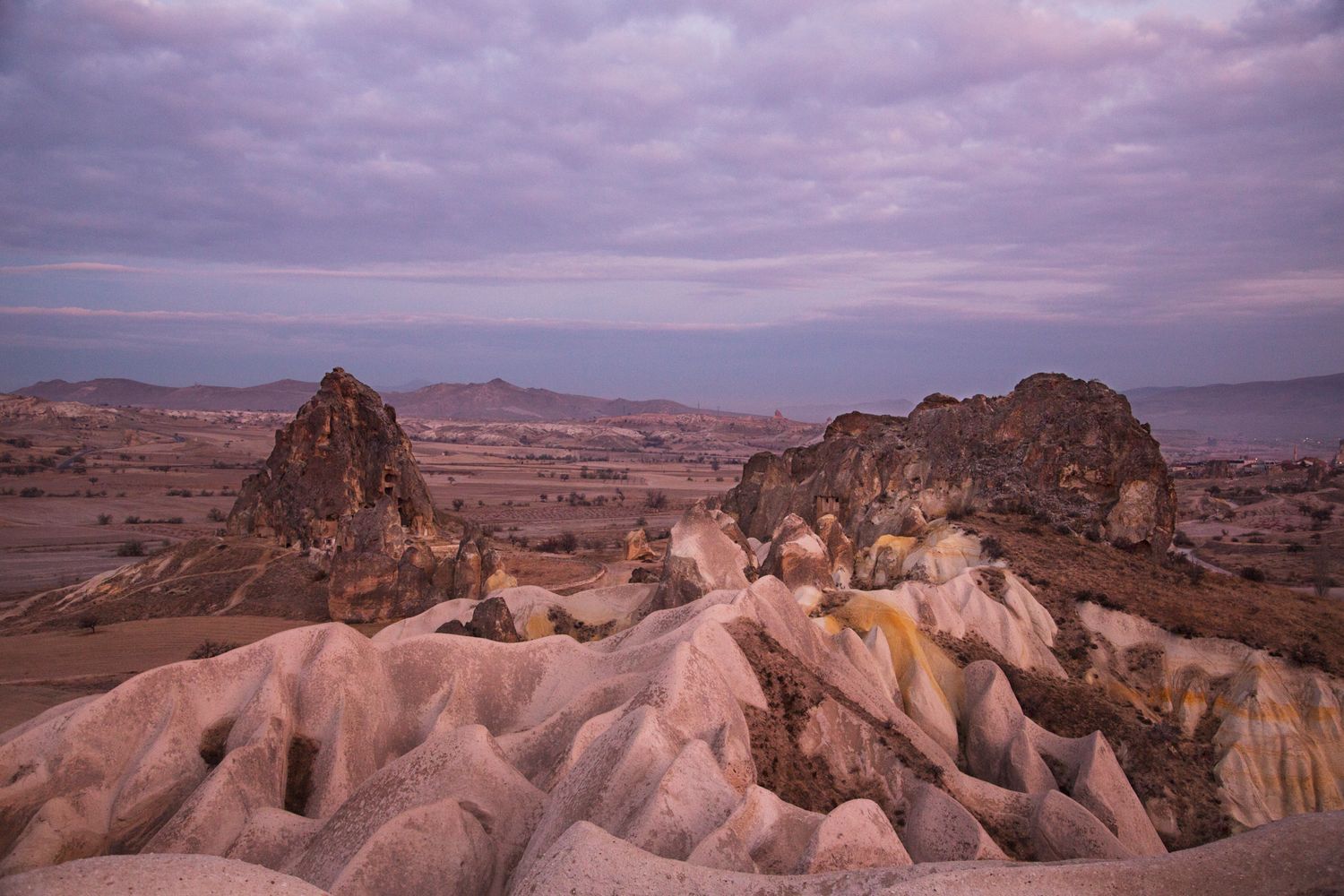 Dramatic purple sunset over Cappadocia's distinctive rock formations and valleys.