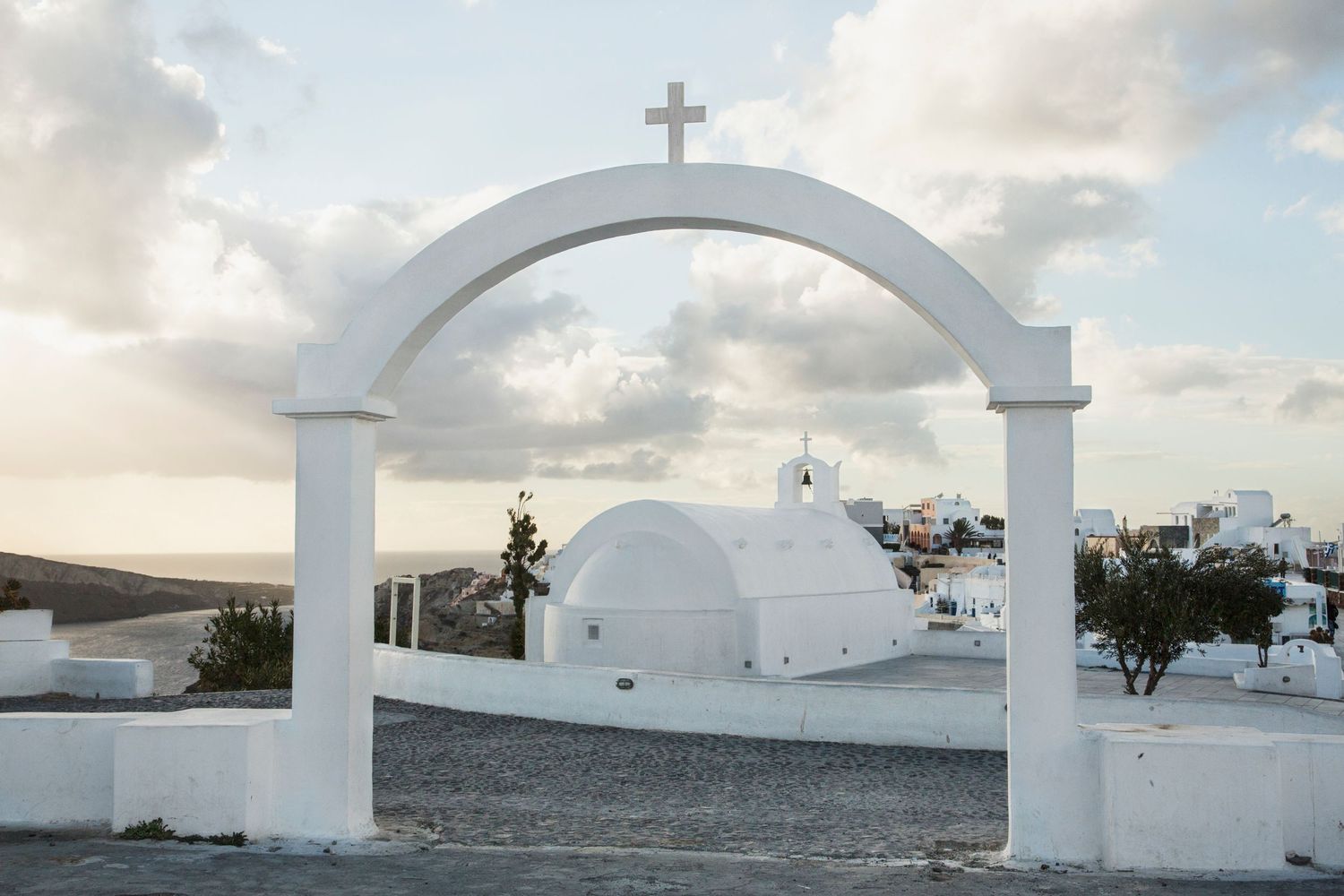White archways and crosses in Mediterranean style architecture against blue sky.