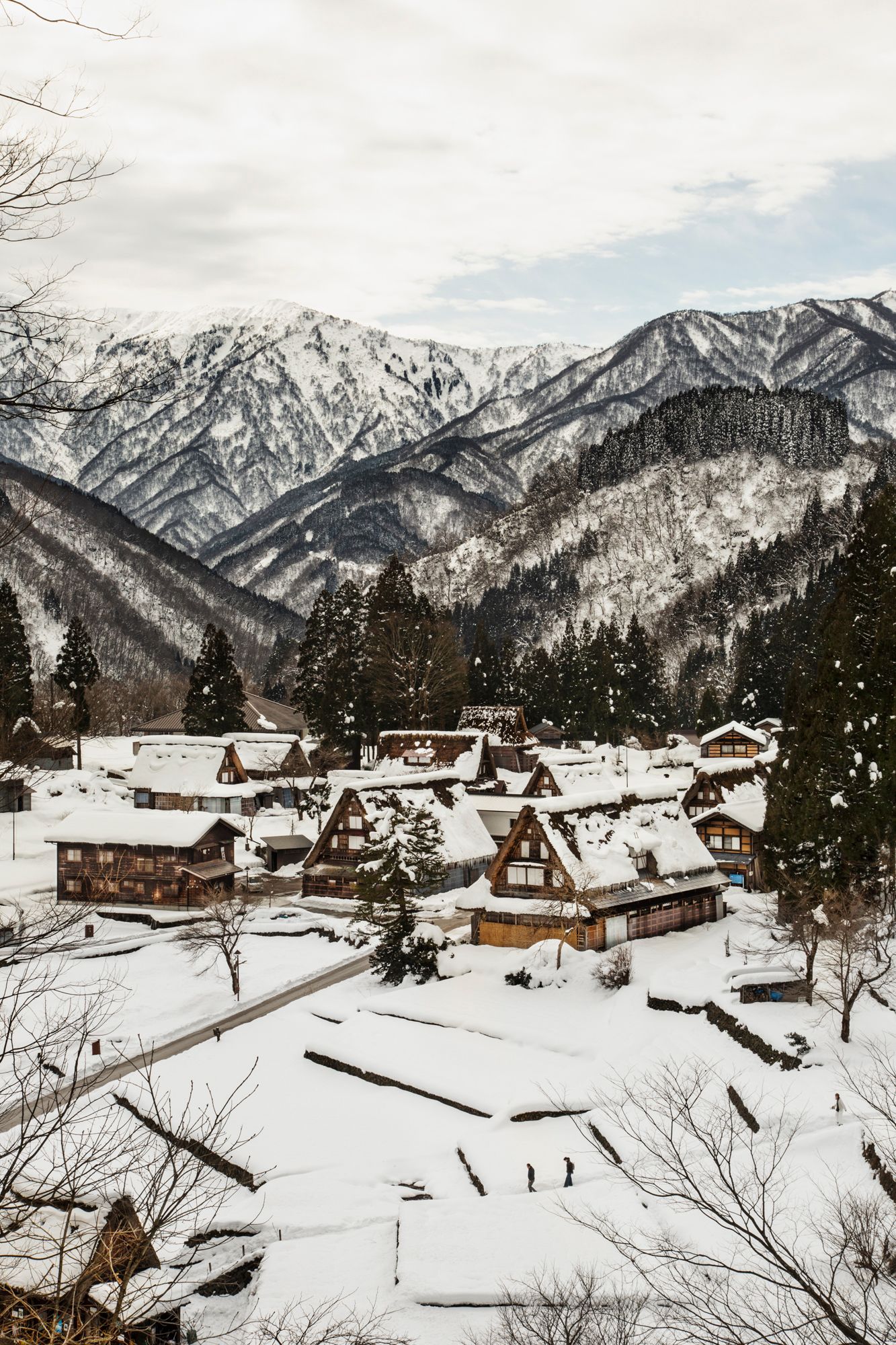 Snow-covered mountain village with traditional wooden houses nestled in a winter landscape.