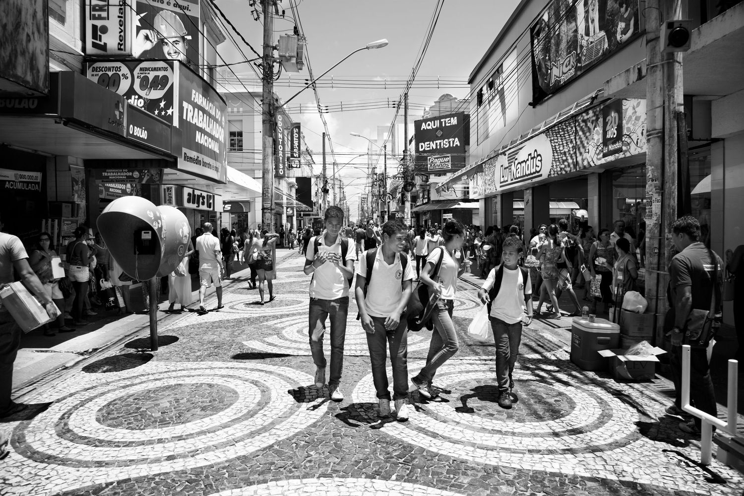 Bustling street scene with geometric patterns on the pavement in black and white.