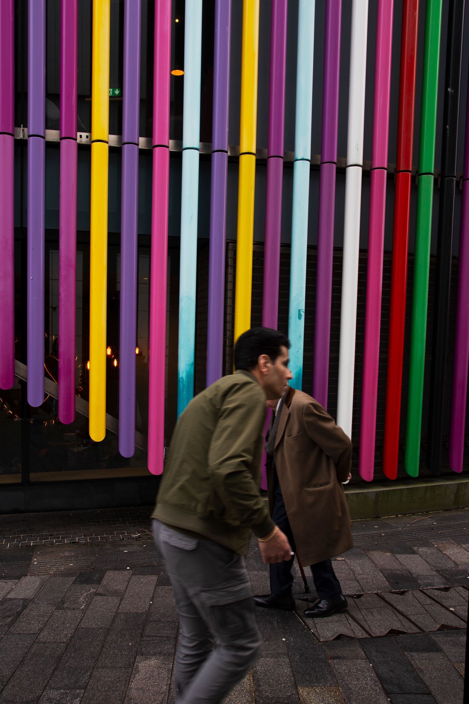Colorful vertical striped wall installation creates vibrant urban backdrop.