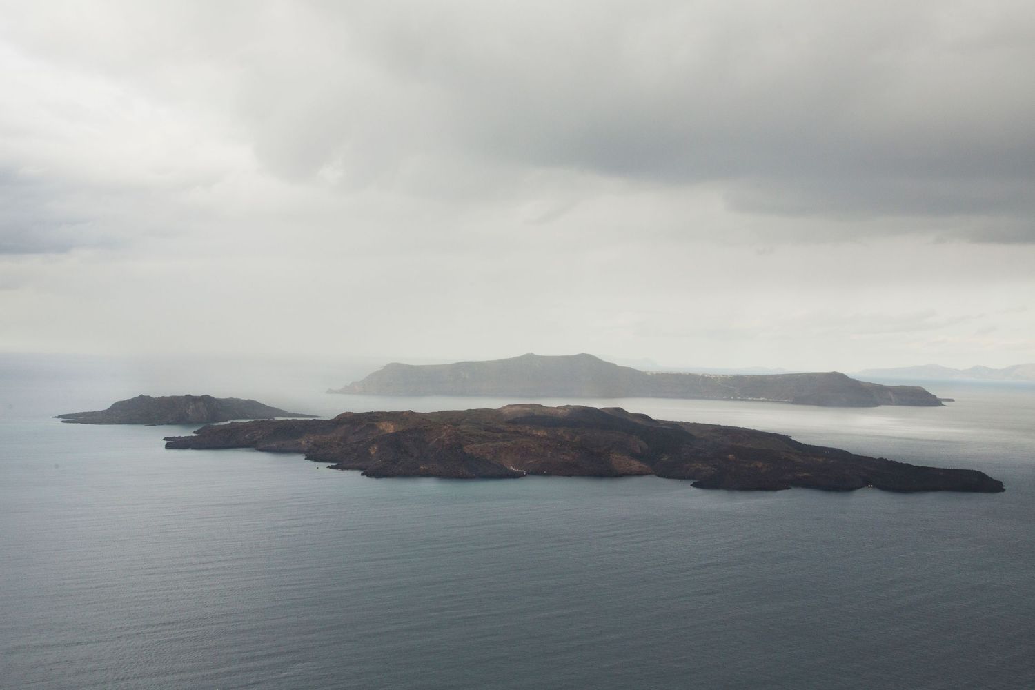 Misty landscape panorama of distant islands and coastline under overcast skies.