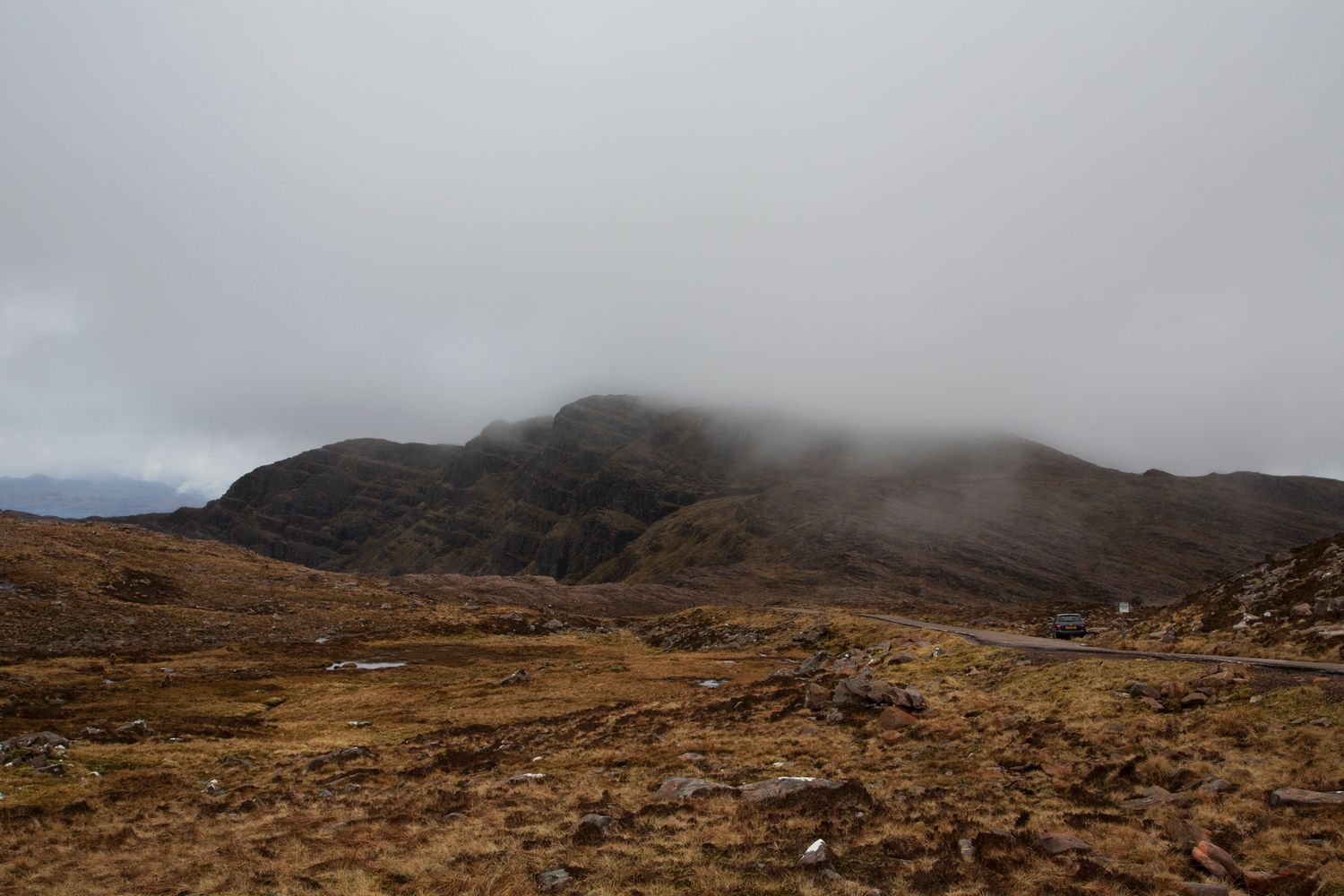 Panoramic mountain landscape with rugged peaks and cloudy skies stretching across a barren wilderness terrain.