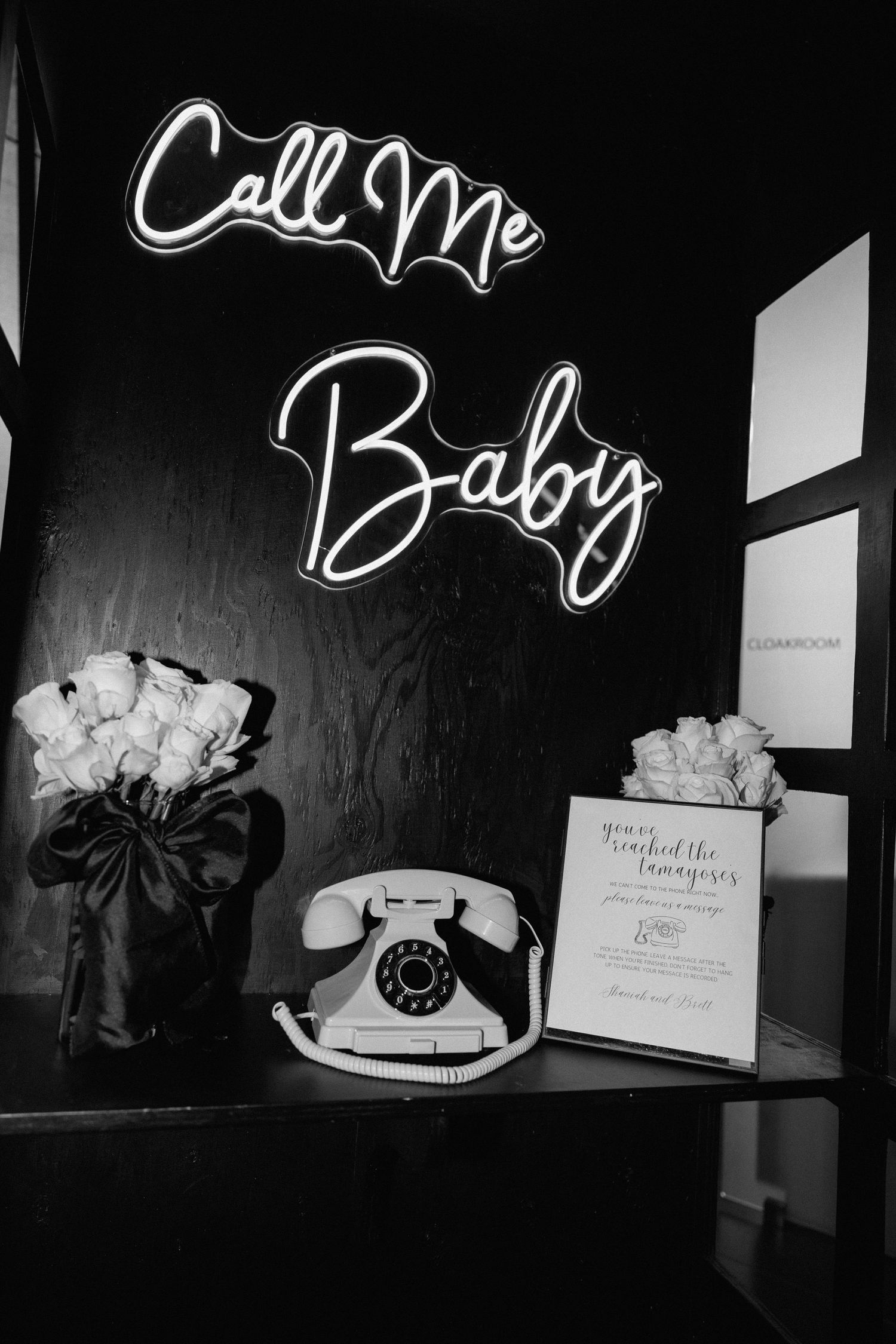 Black and white artistic photographs of vintage rotary phones and neon signs displayed in a gallery setting.