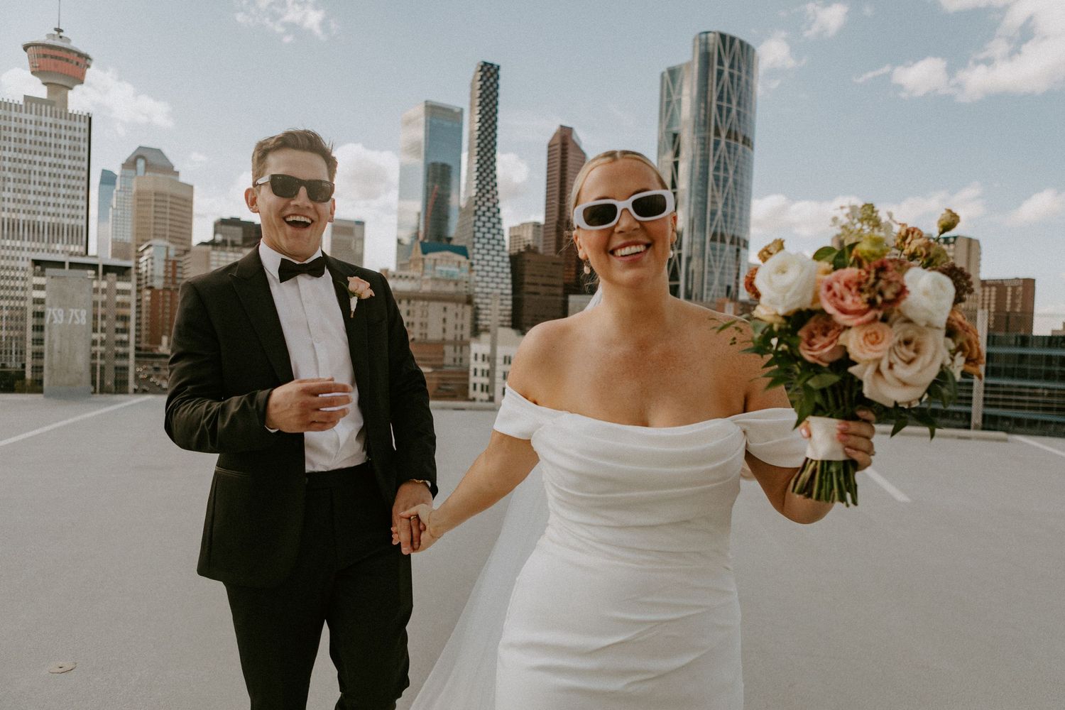 Wedding couple stands on rooftop with Calgary Tower and downtown skyline visible behind them.