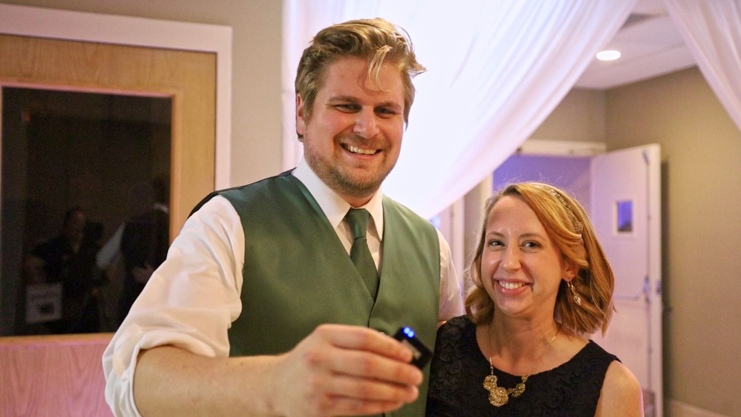 Casual indoor celebration with guests in formal attire sharing candid moment.