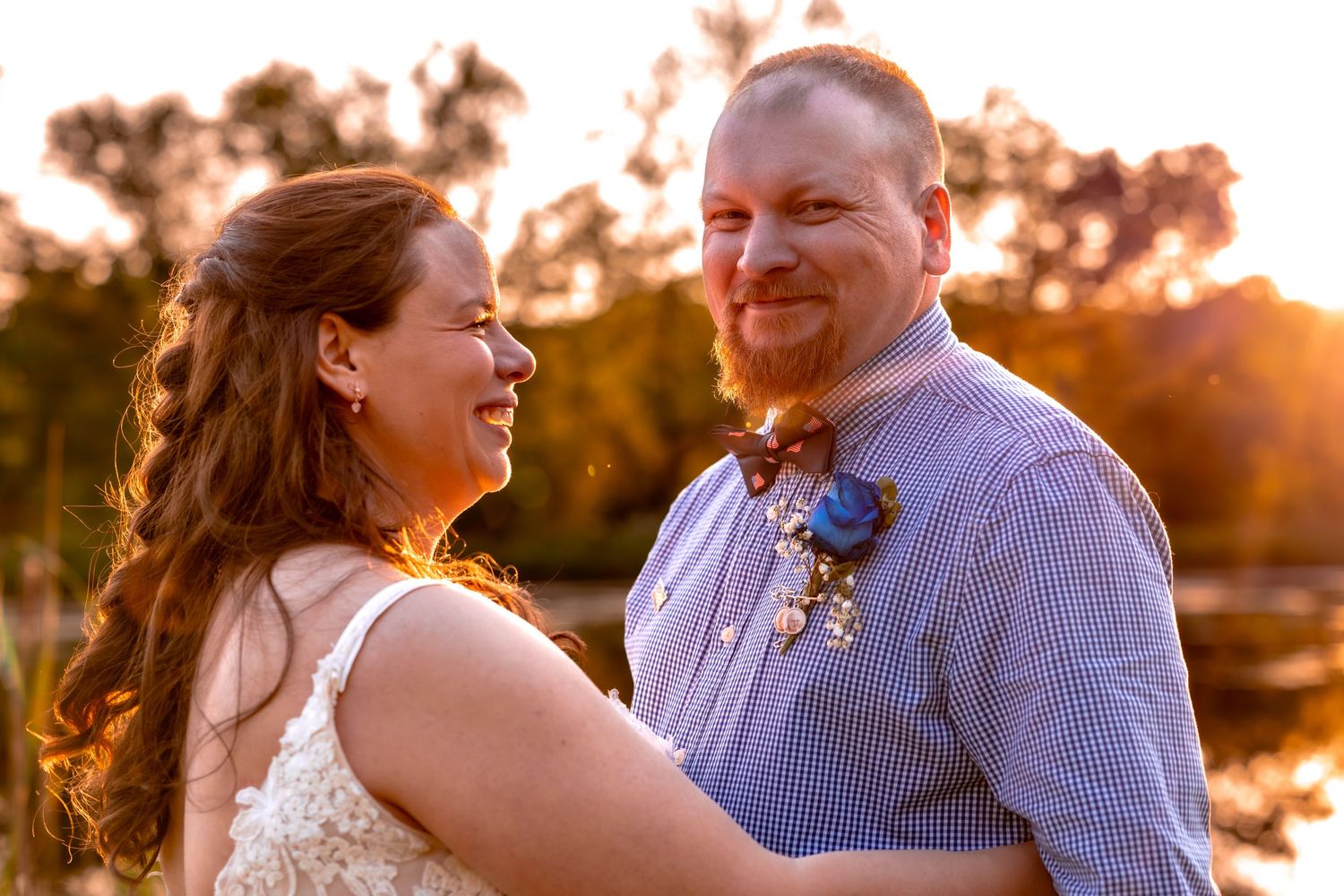 A couple shares a joyful moment together during their sunset wedding photoshoot by a lake.