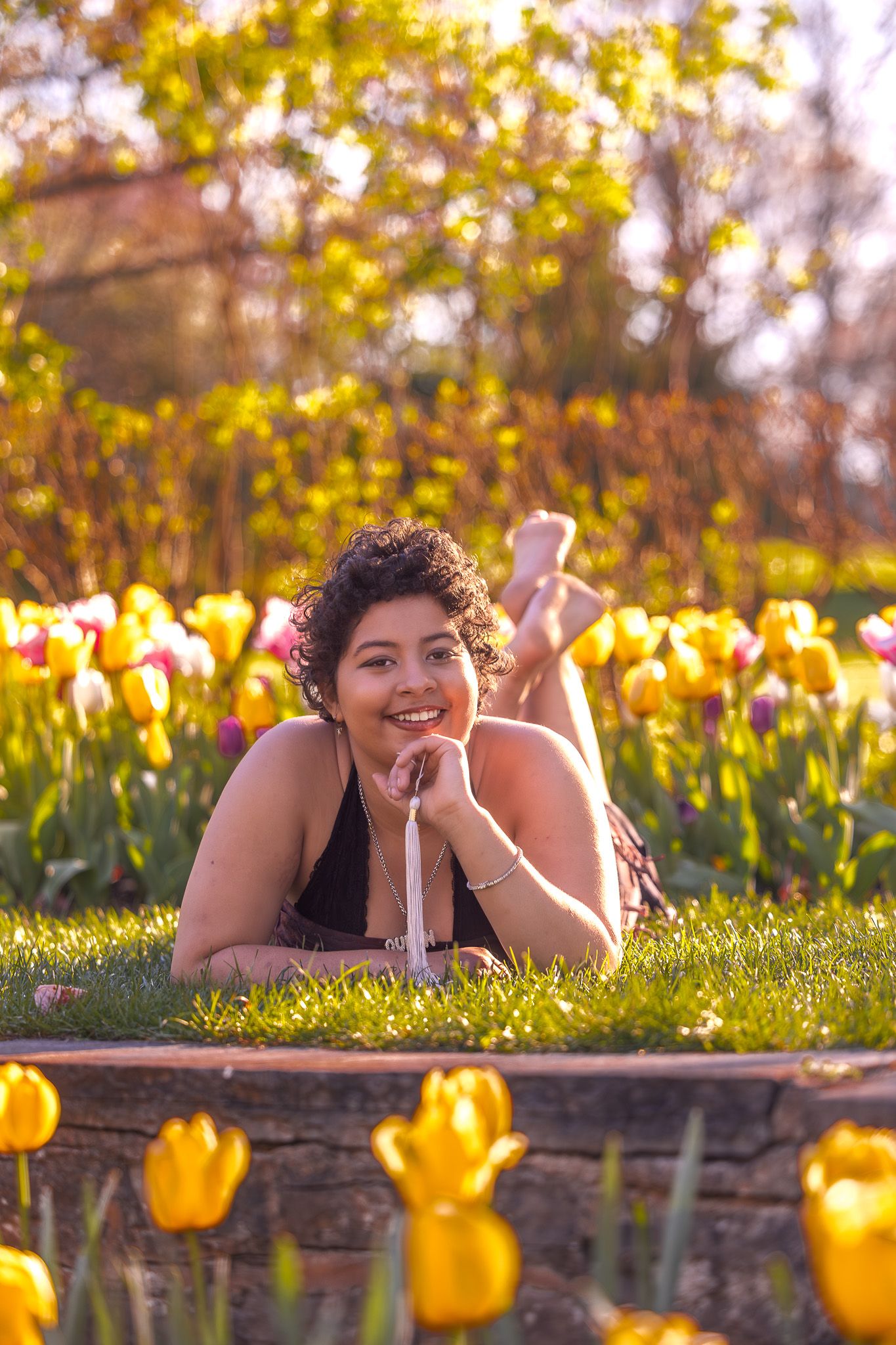 Tulips bloom in foreground as someone relaxes in sunny spring garden.