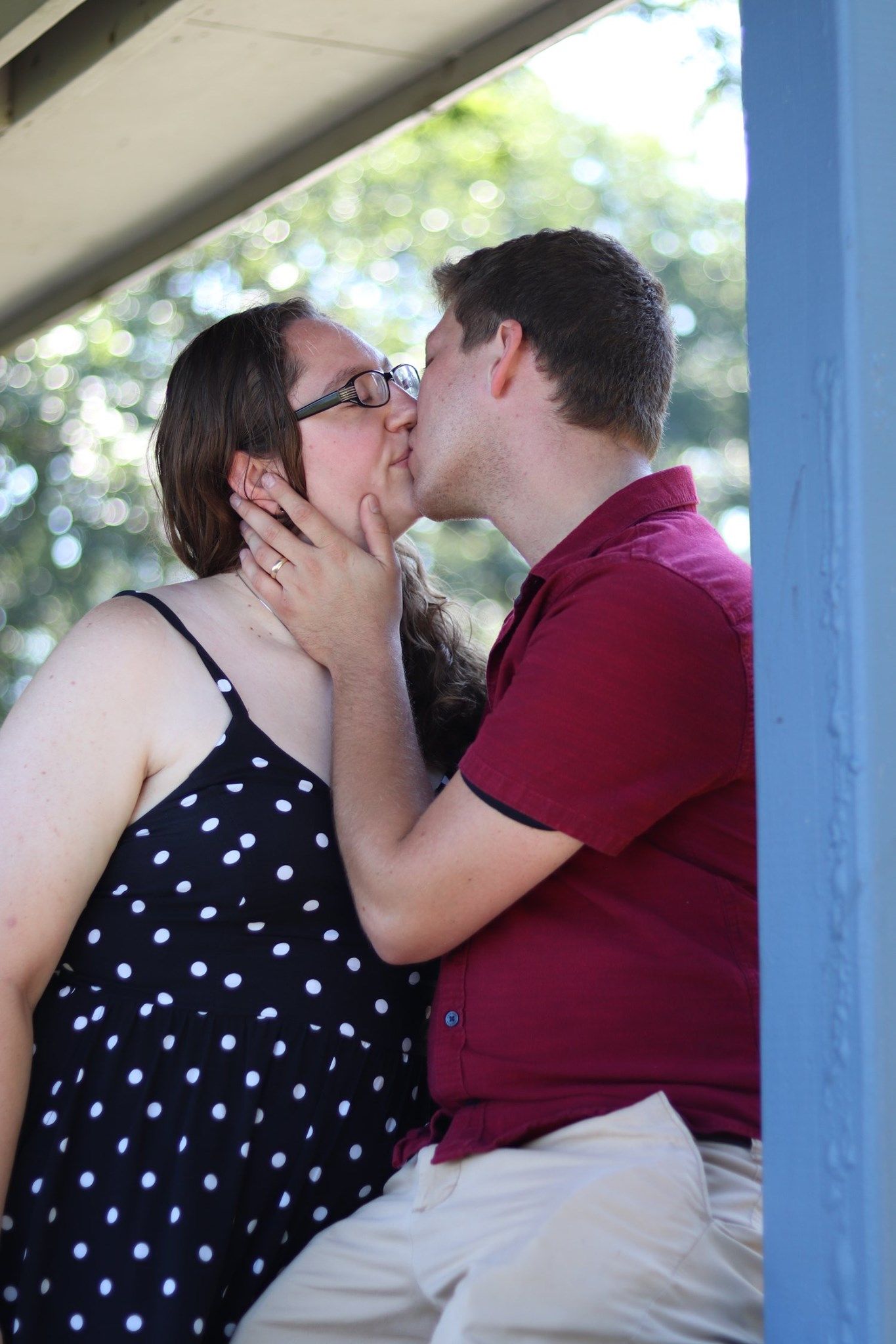 A romantic moment shared between a couple, with the woman in a polka dot dress and the man in a burgundy polo shirt.