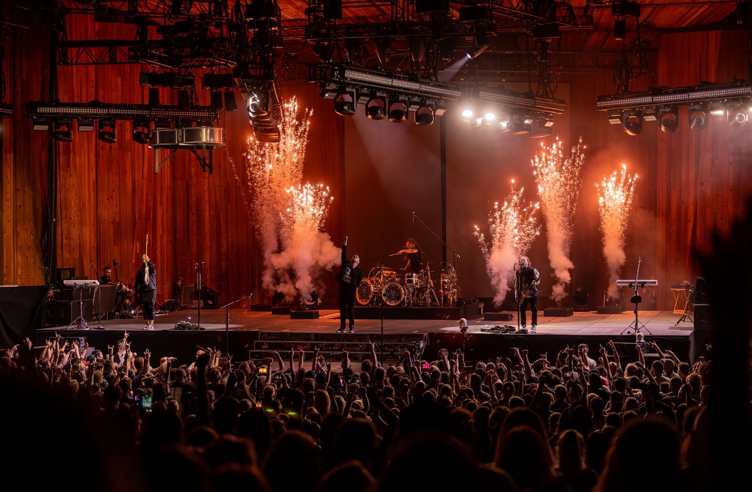 Rock concert performance with pyrotechnic effects and silhouetted crowd.