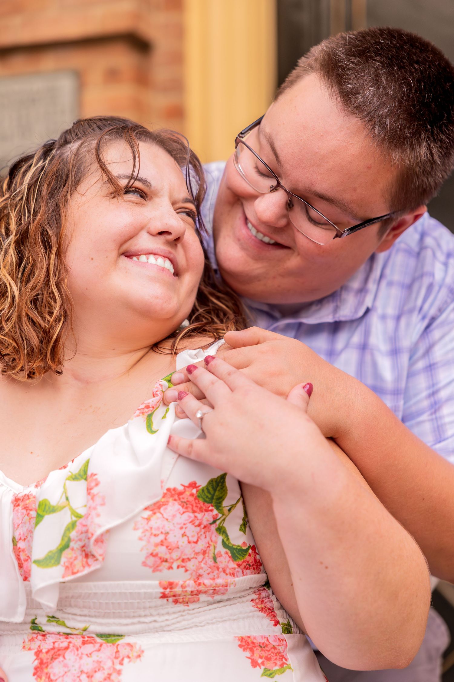 A happy couple sharing a tender moment together outdoors, with the woman wearing a floral dress.