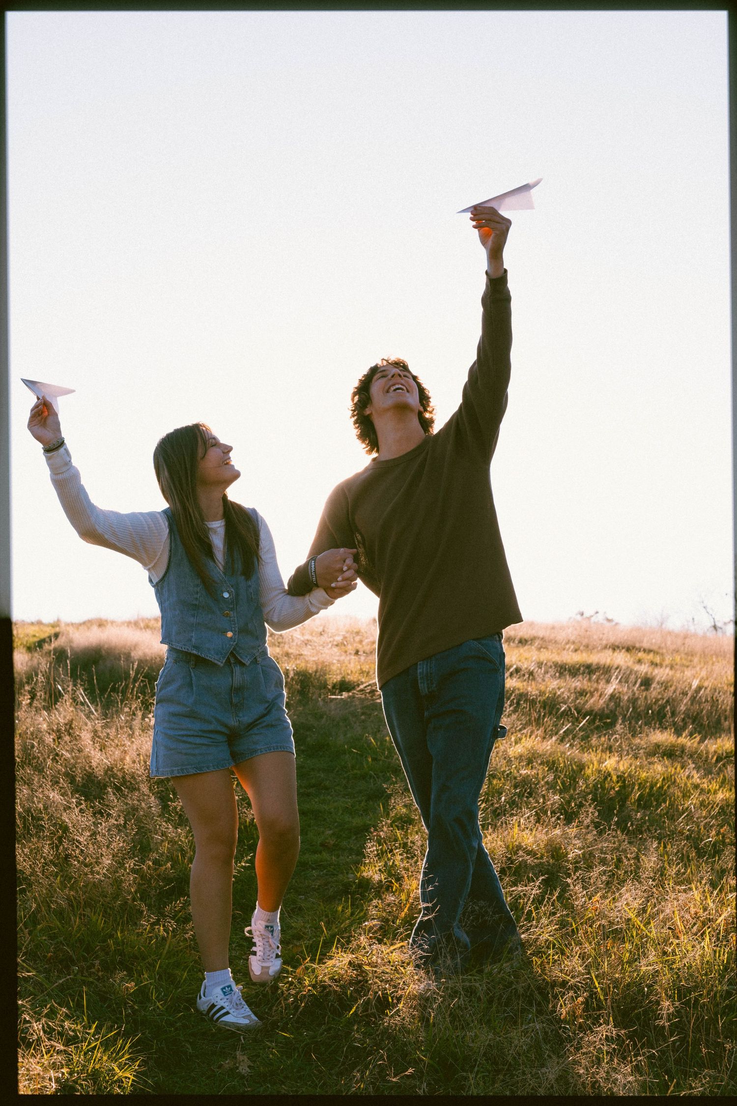 Two people dancing and celebrating joyfully in a golden field at sunset.