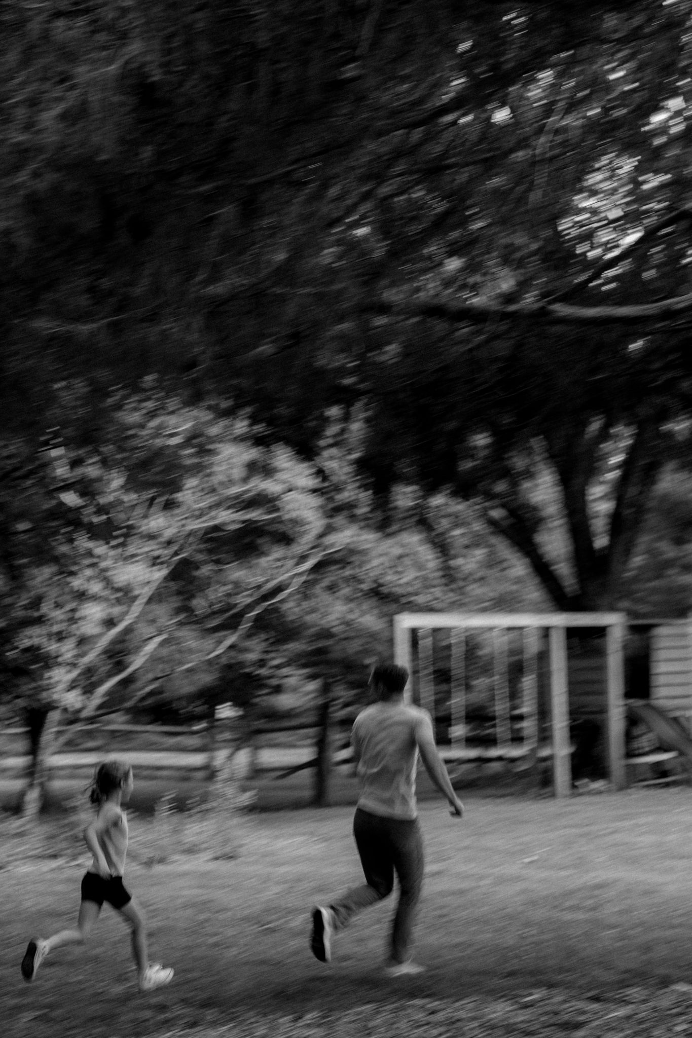 Group playing and running across a grassy yard in black and white.
