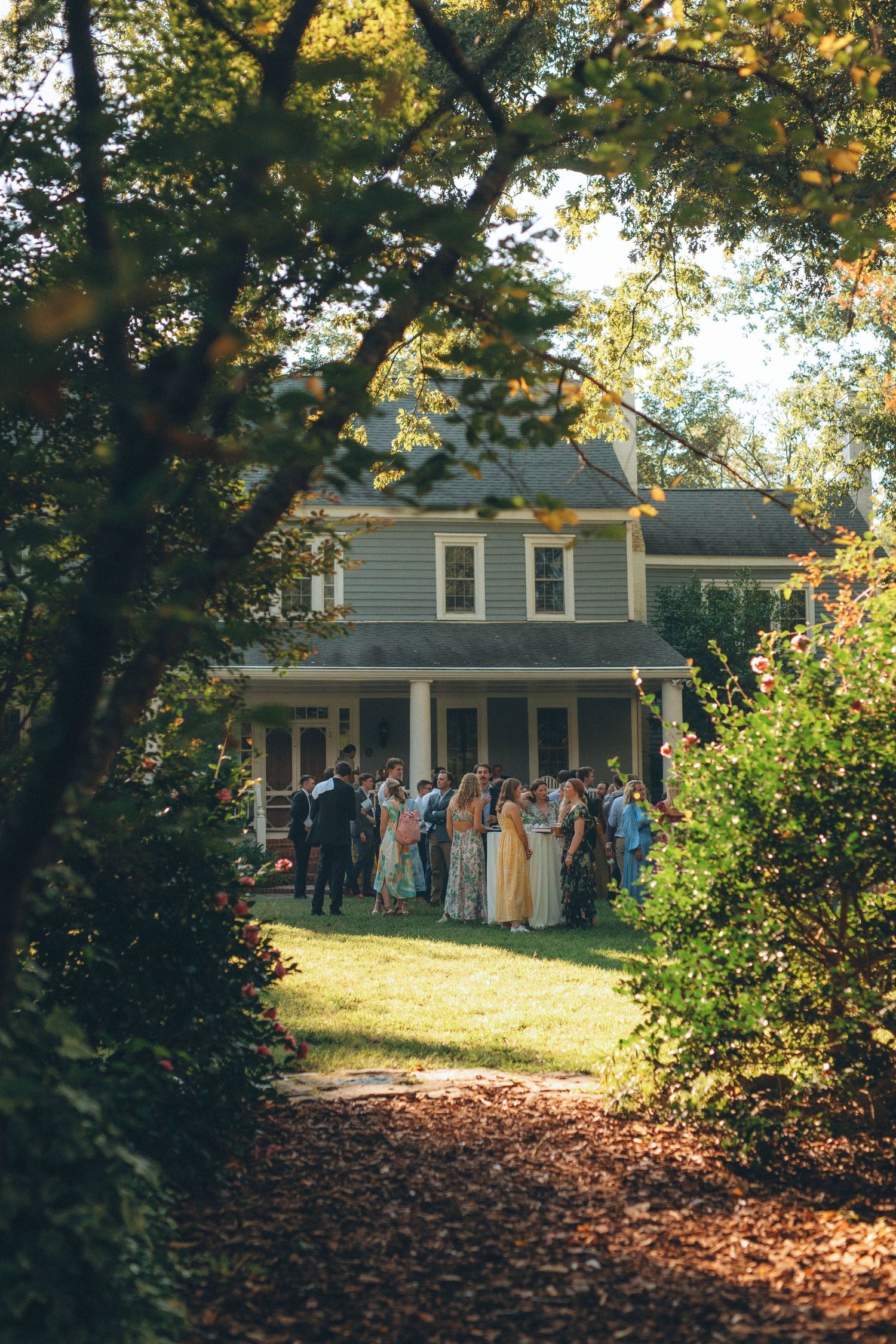 An autumnal wedding scene outside a classic house with guests gathered on the lawn.